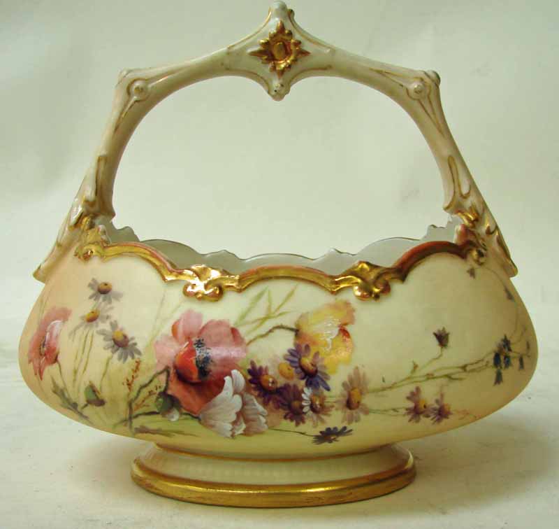 A Royal Worcester blush ivory porcelain handled basket of oval footed form, printed, gilt and