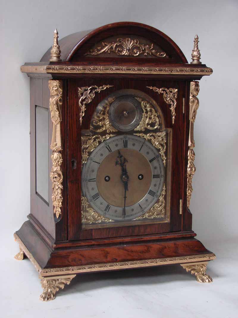 A late 19th century oak and gilt metal bracket clock, arch top case with flame finials, applied