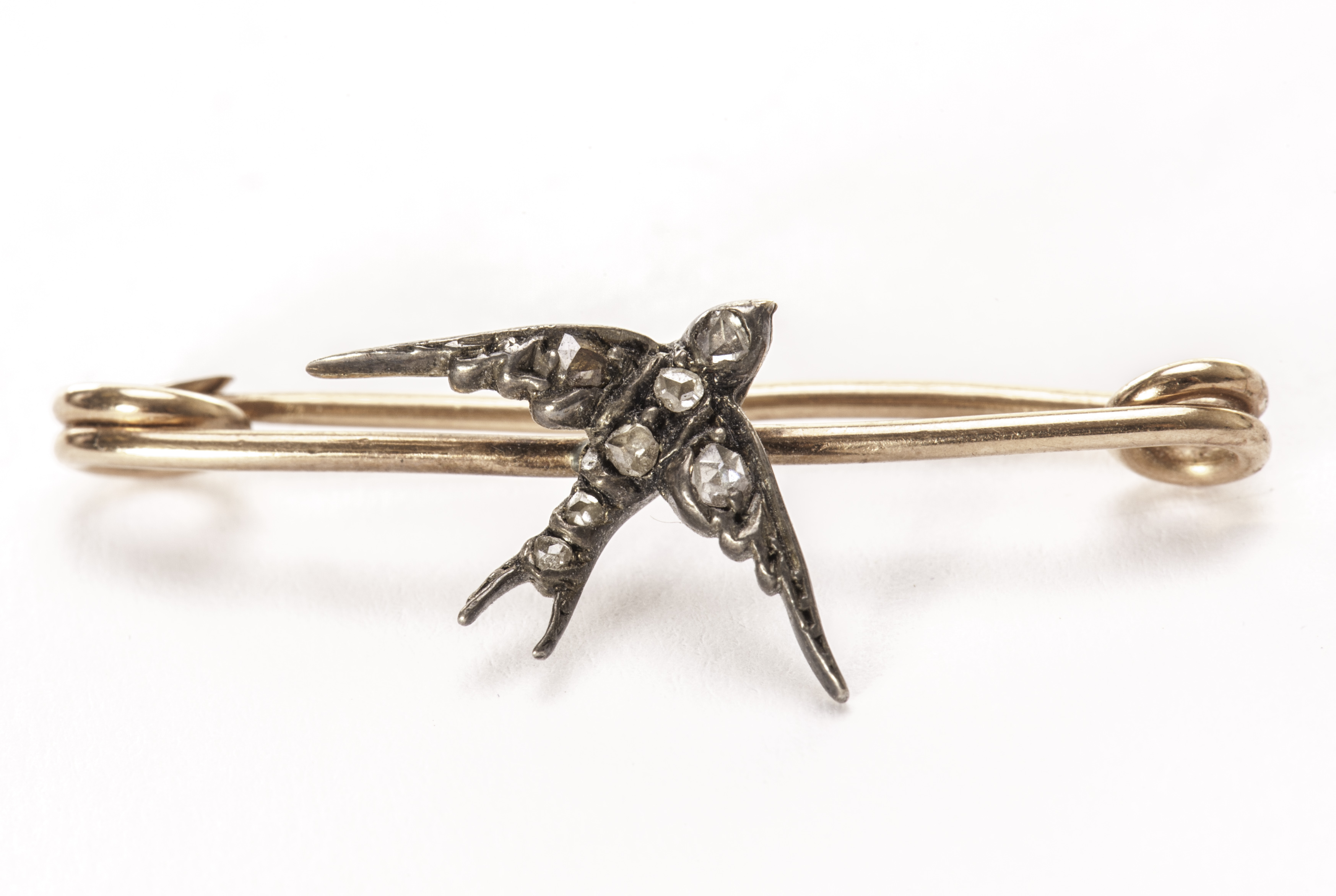 A Victorian gold, silver and diamond set bar brooch, having a swallow set with rose cut stones on