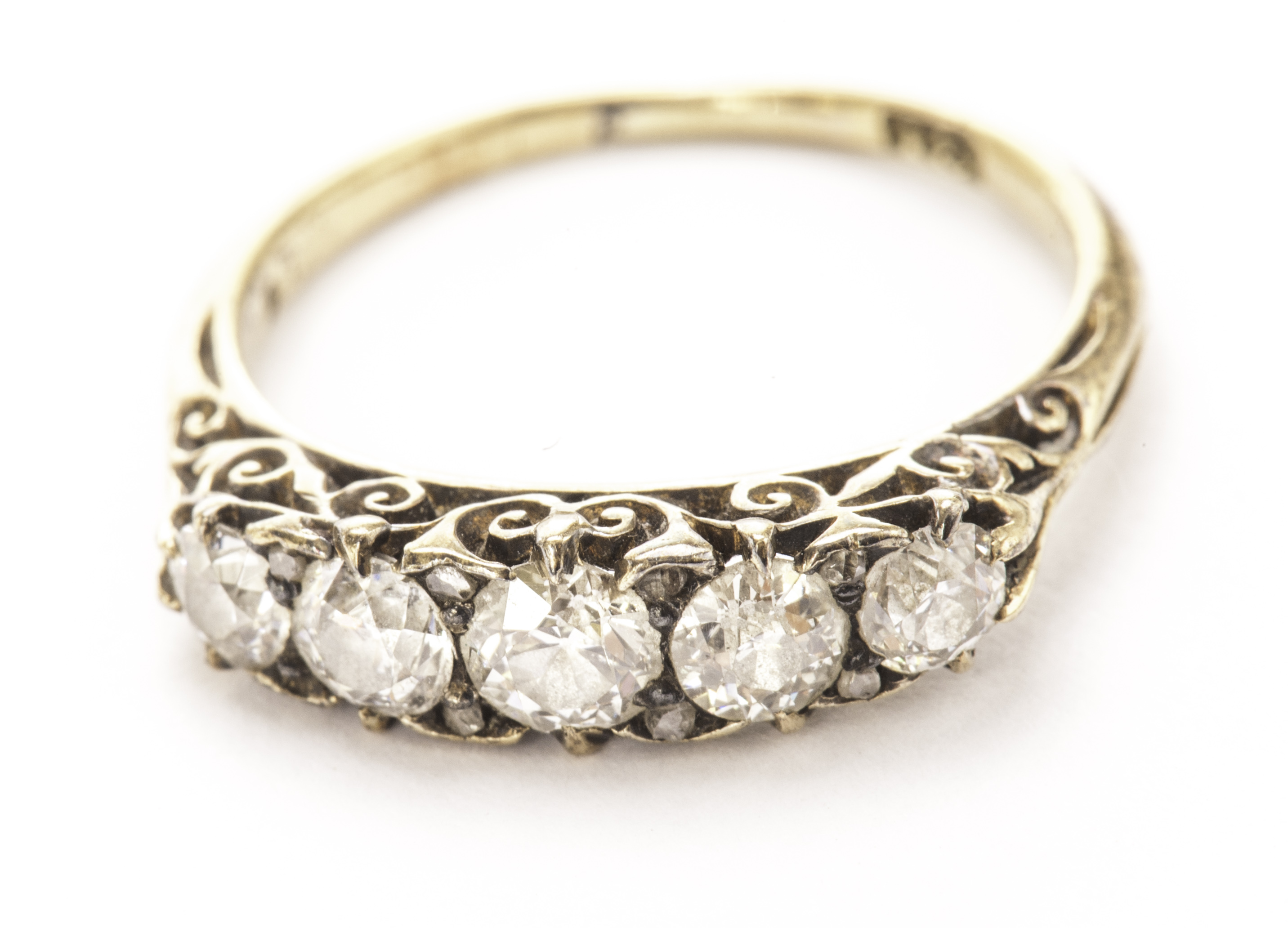 An Edwardian five stone diamond ring, the graduated old cuts of approx 1.4ct in scroll gallery