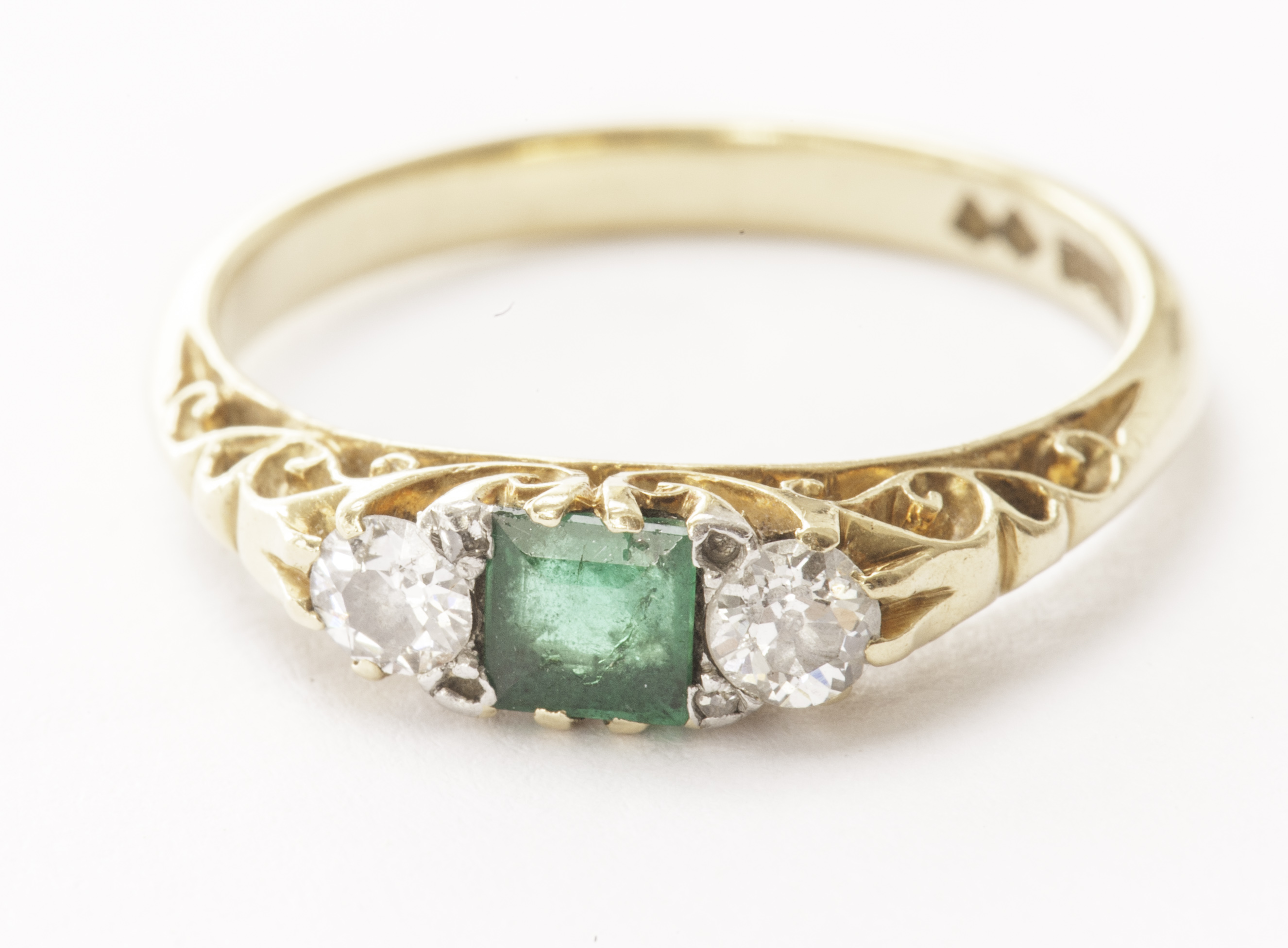 A Victorian or Edwardian three stone emerald and diamond ring, having a square cut central green