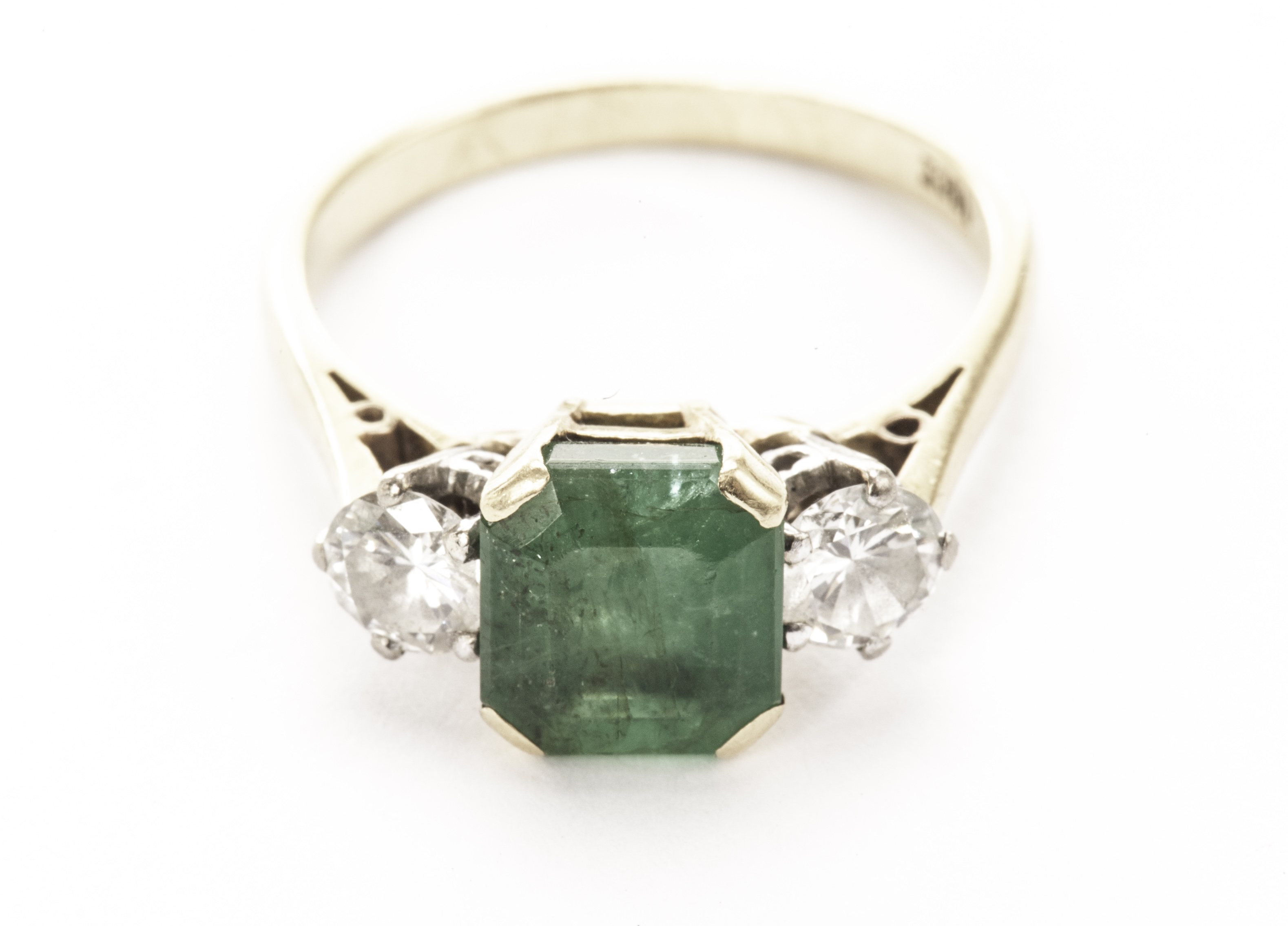 A nice emerald and diamond three stone dress ring, the square style cut green stone having a