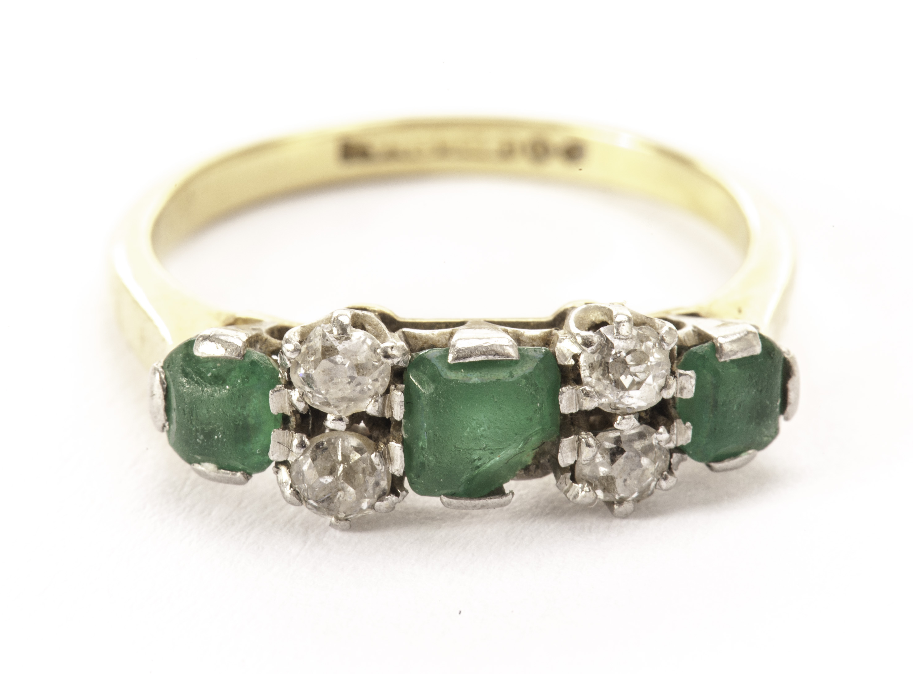 An emerald and diamond dress ring, having a central square cut green stone, AF, flanked by a pair