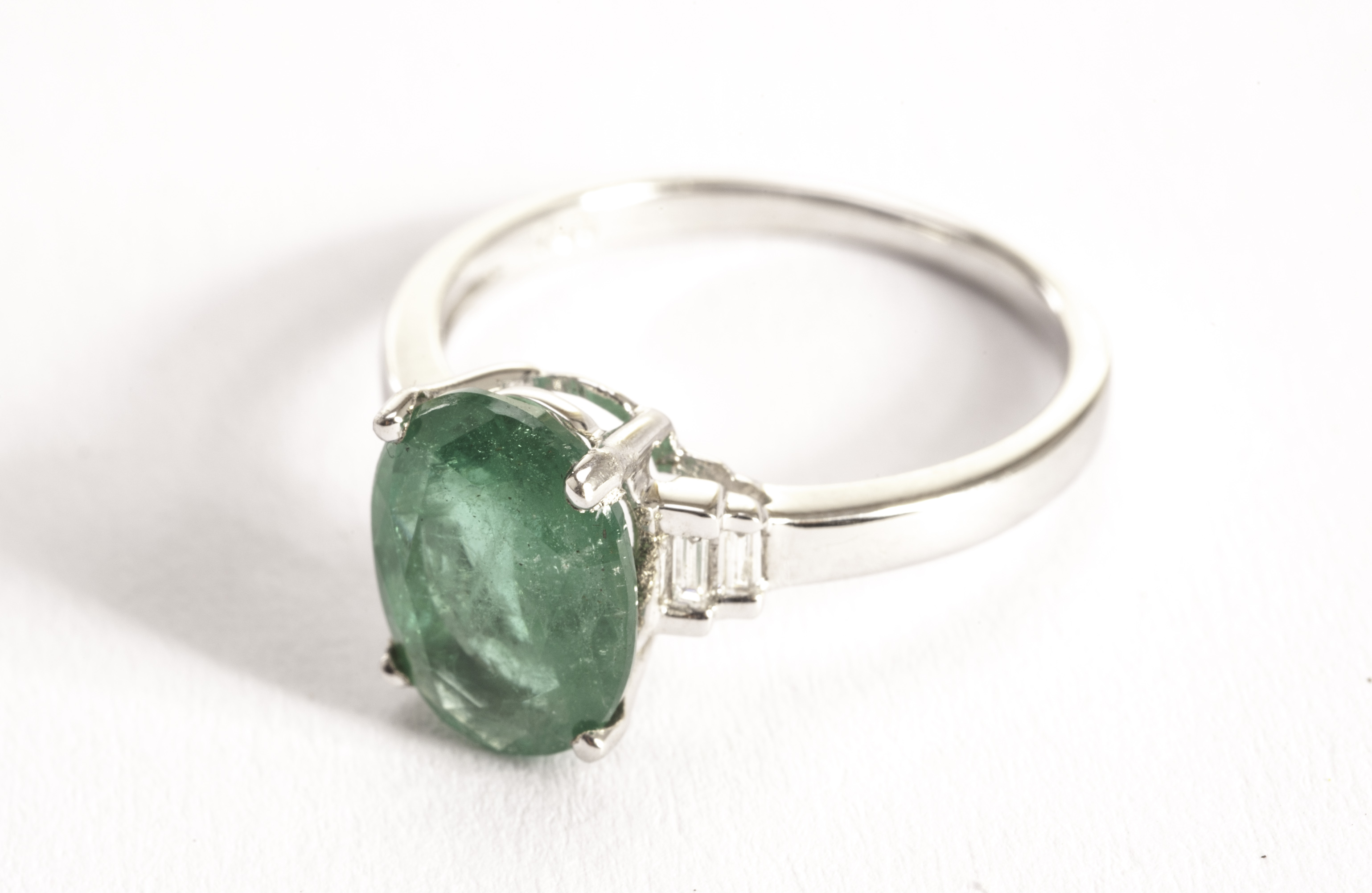 An impressive emerald and diamond dress ring, the large oval cut green stone of approx 2.17ct in a