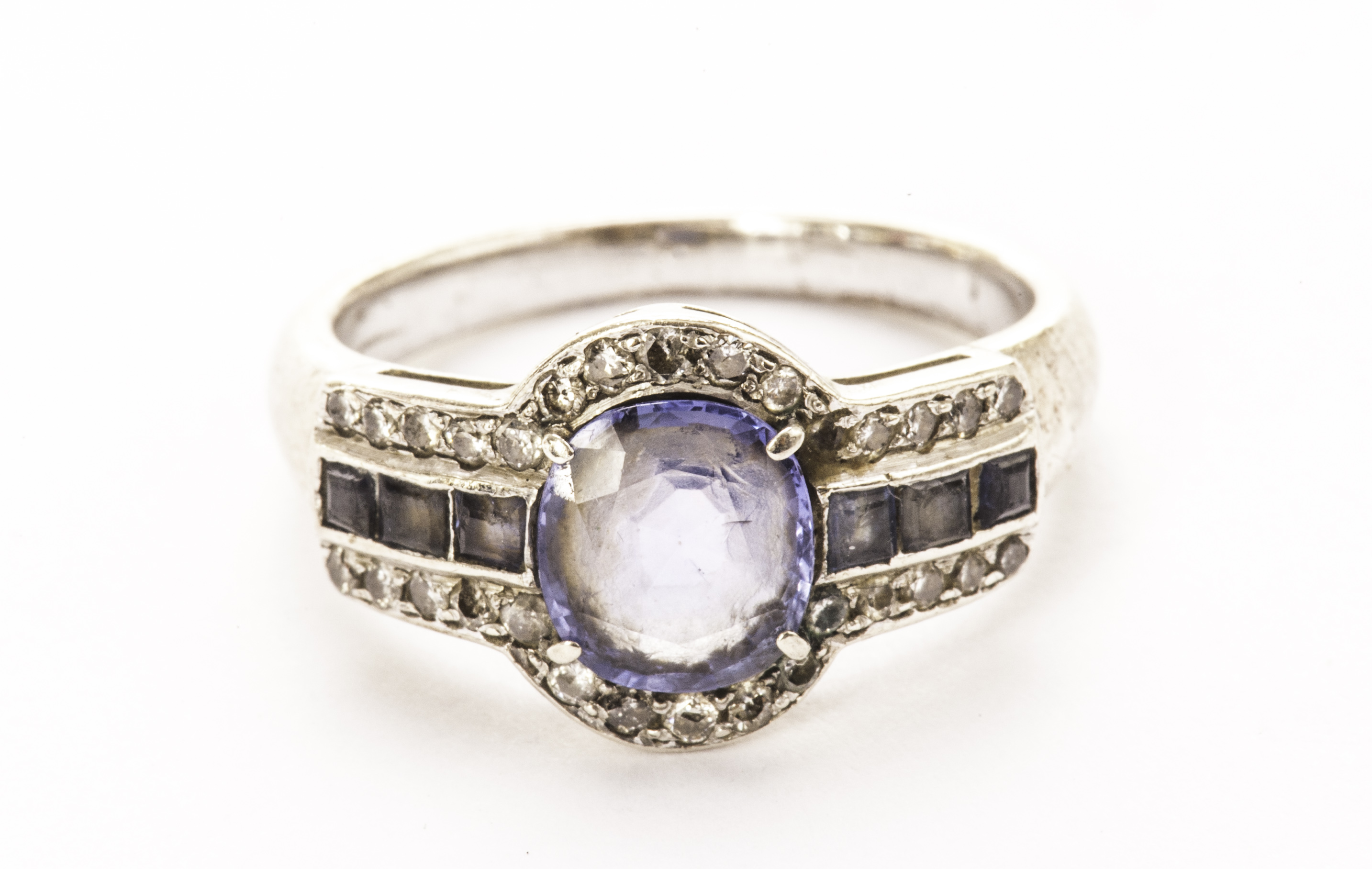 A sapphire dress ring, the central oval cut stone flanked by square cut blue stones and surrounded