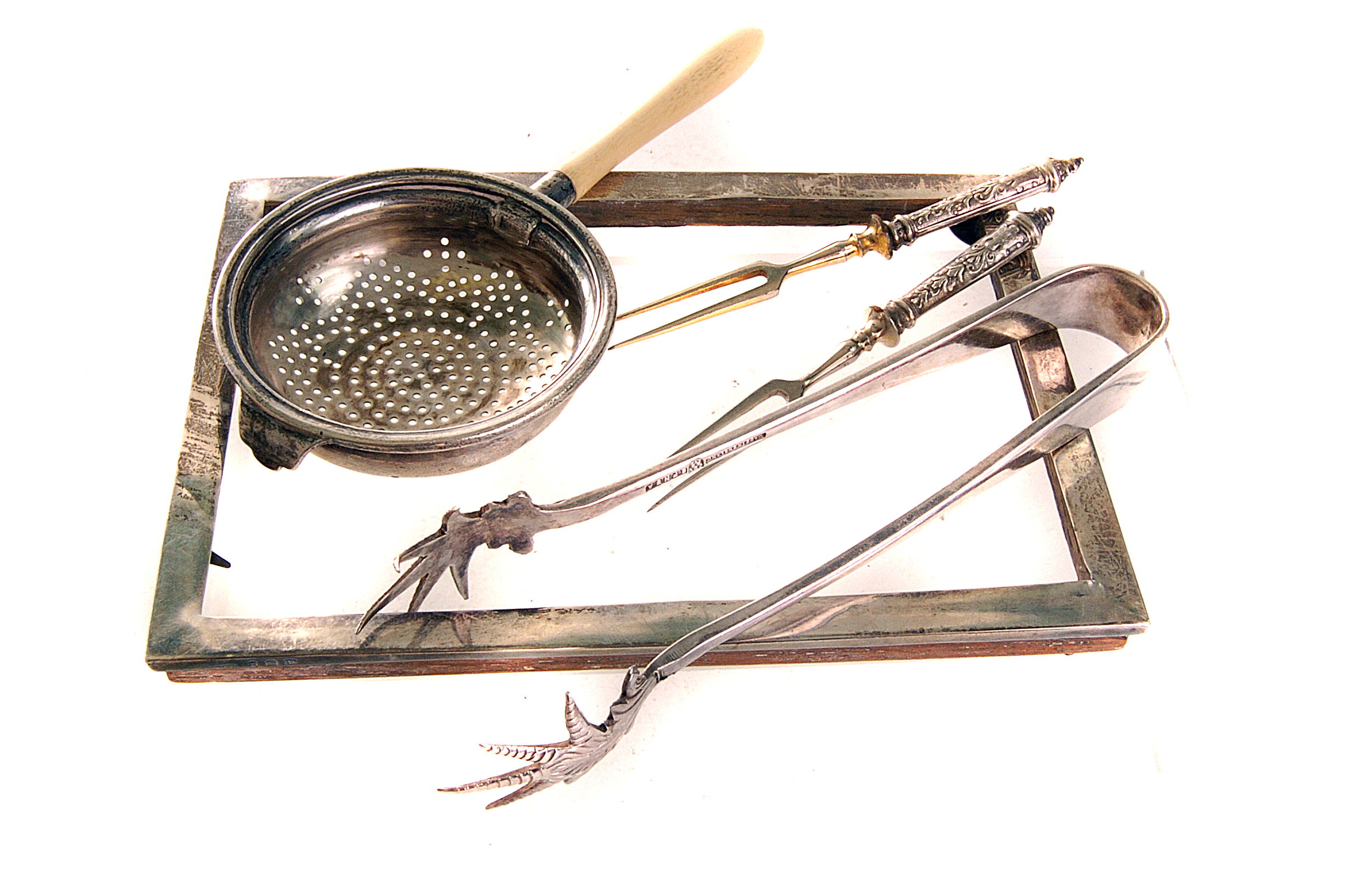 A silver and ivory handled tea strainer, together with a silver photograph frame, a pair of silver