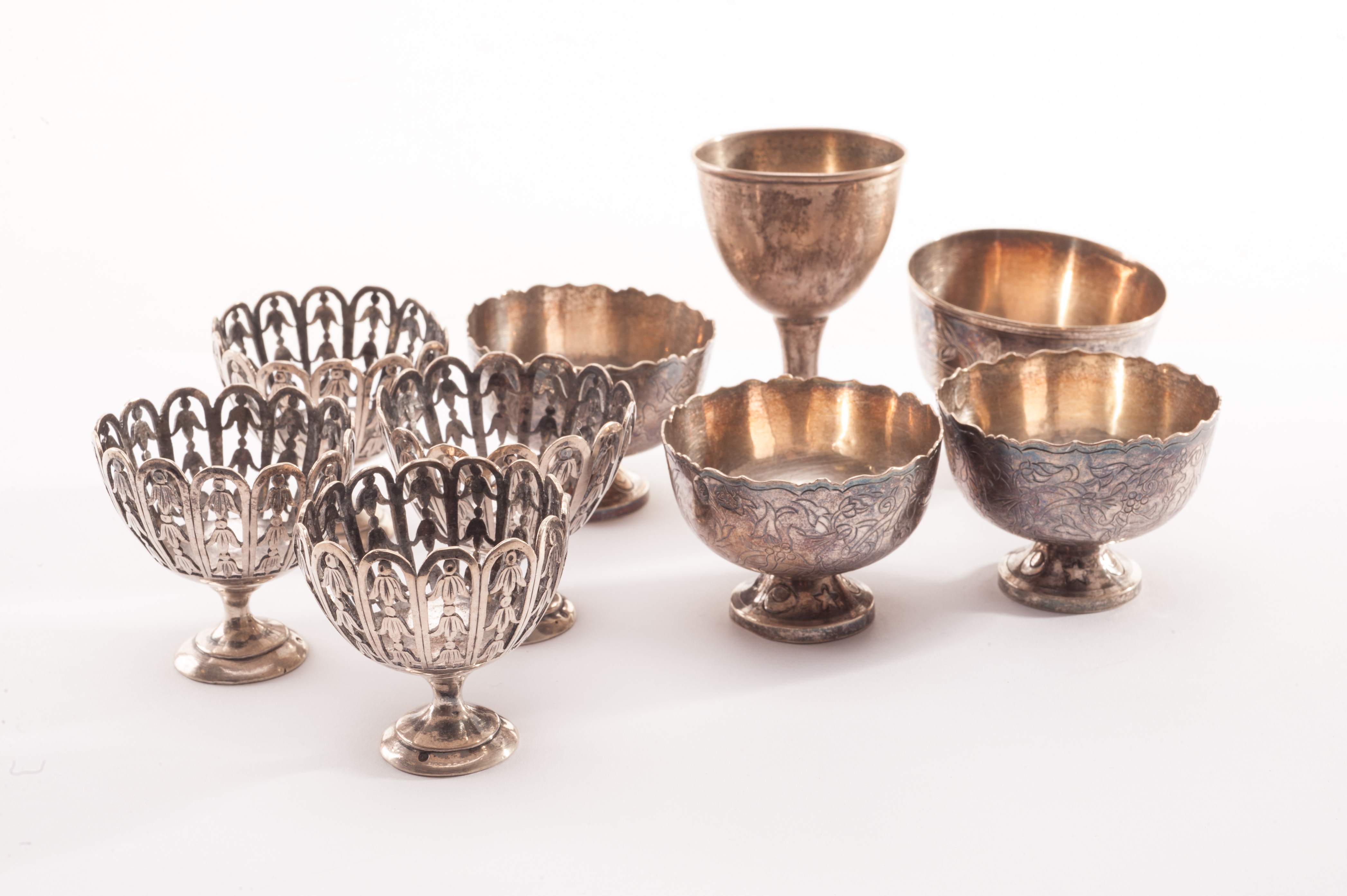 A set of four silver eggcups, with pierced bodies and decorated with floral design together with a