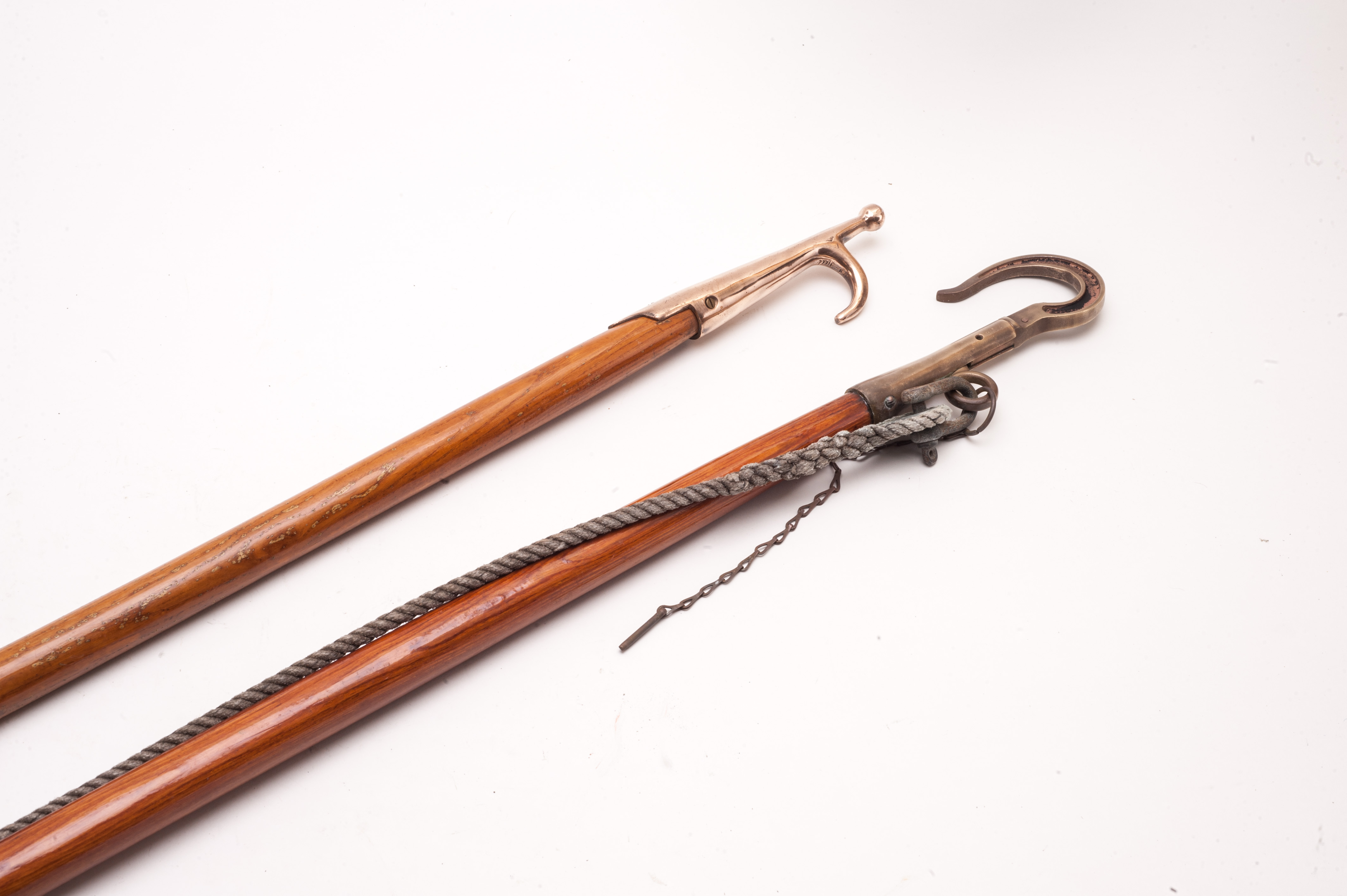 Two useful boat hooks, both on wooden poles, one polished bronze with single hook and the other