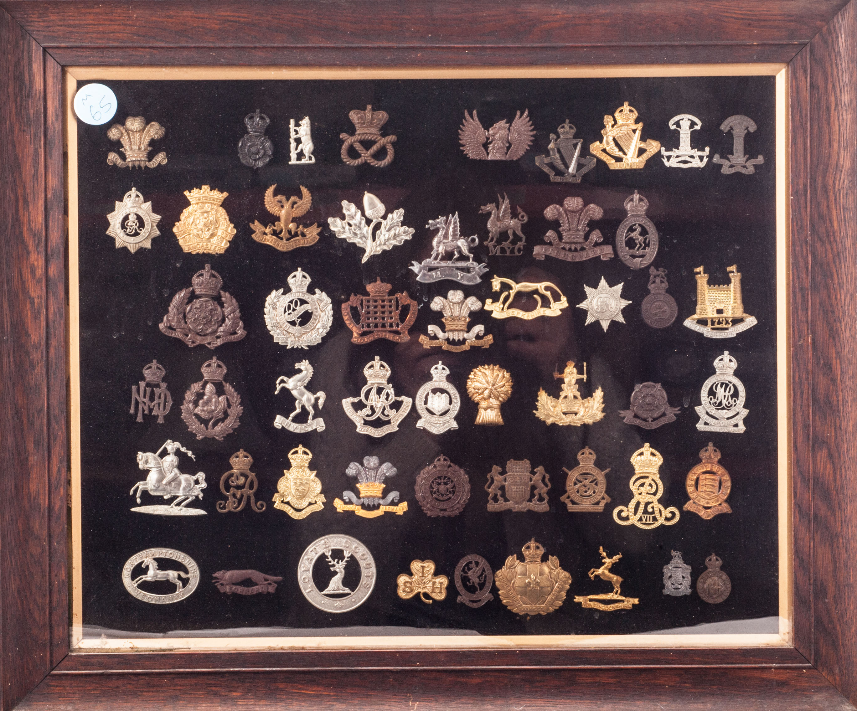 A framed collection of British Army cap badges, comprising Yeomanry and Welsh Regiments, also