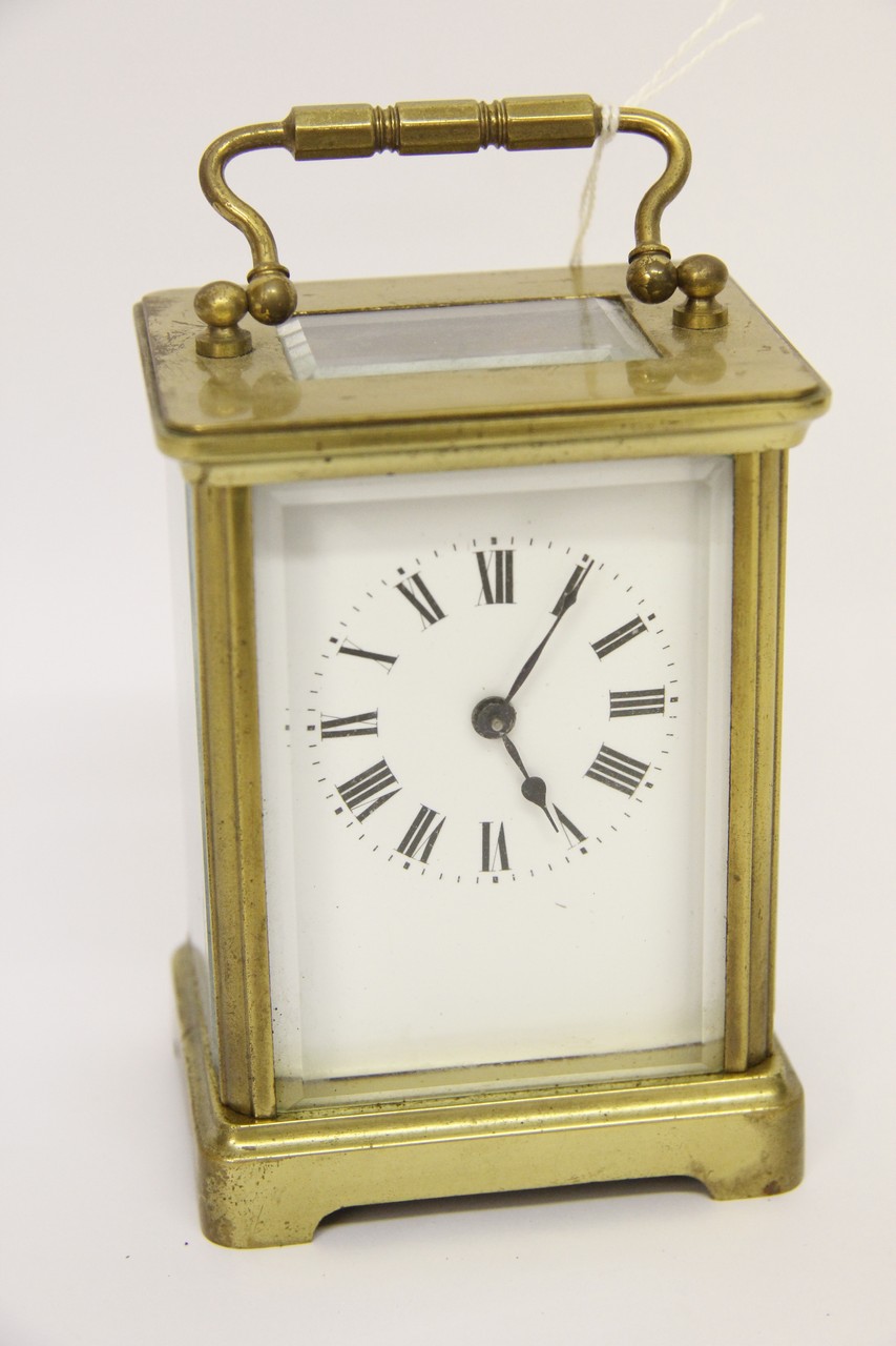 A brass carriage clock with enameled dial