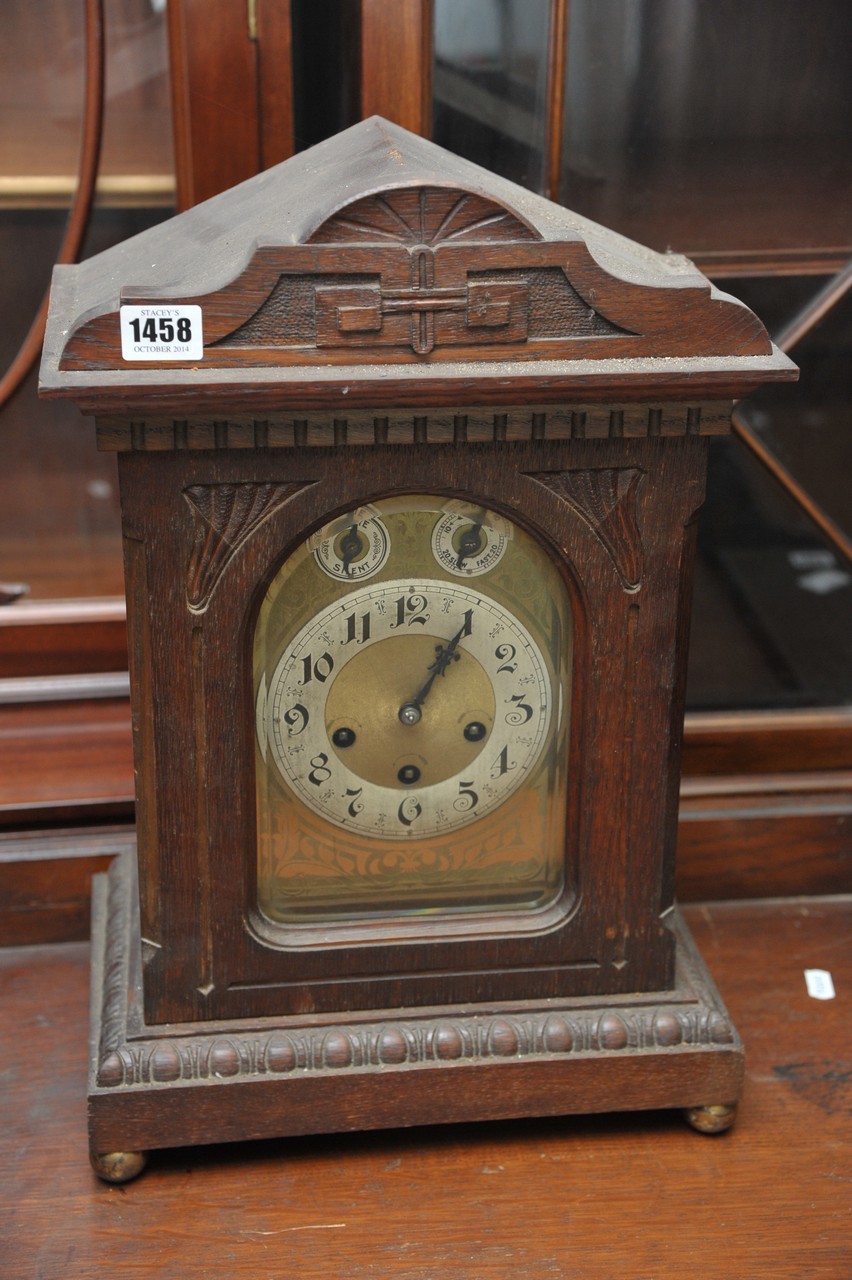 An oak cased mantle clock, having arch shaped dial, the chapter ring with Arabic numerals