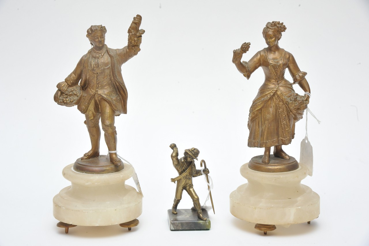 A pair of metal figures of fruit sellers and a small boy holding a crook