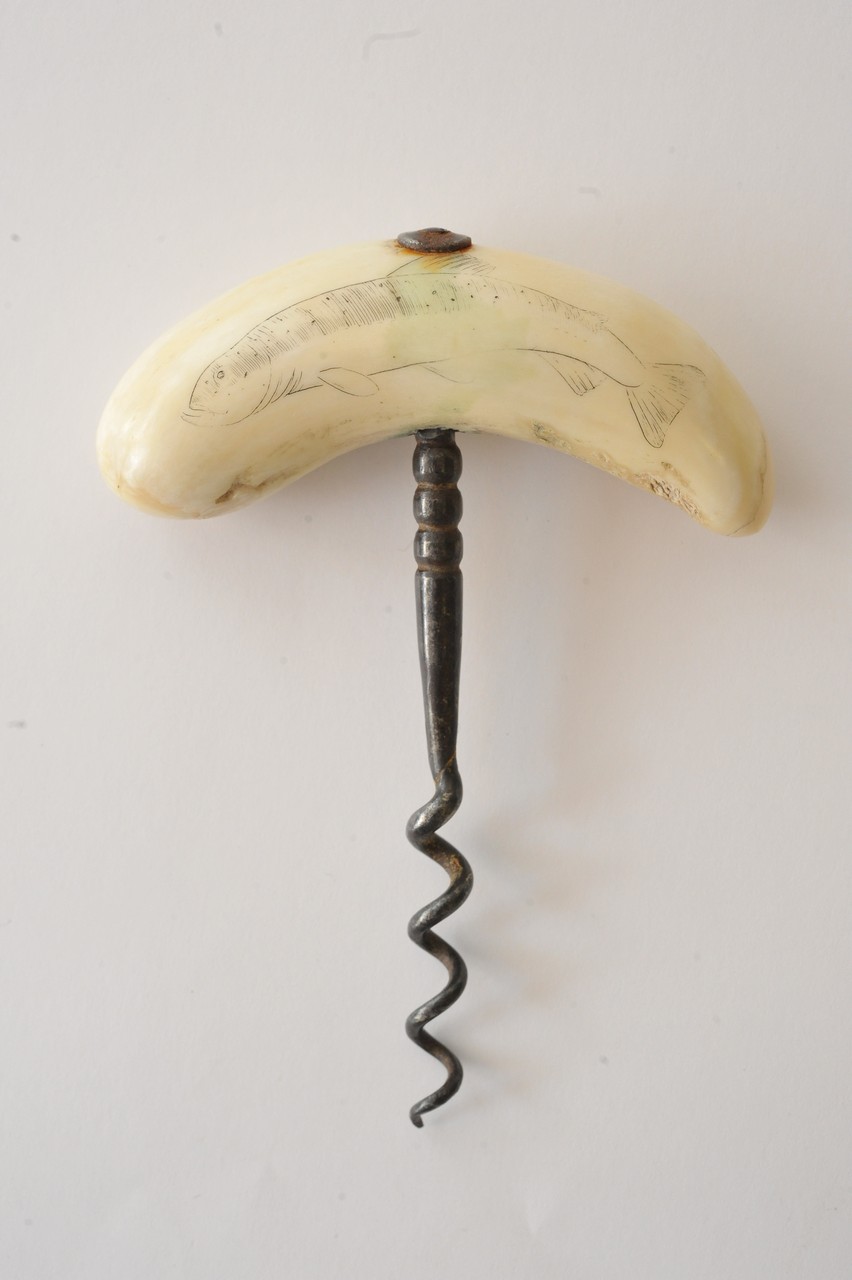 An old corkscrew having scrimshaw handle carved with a fish