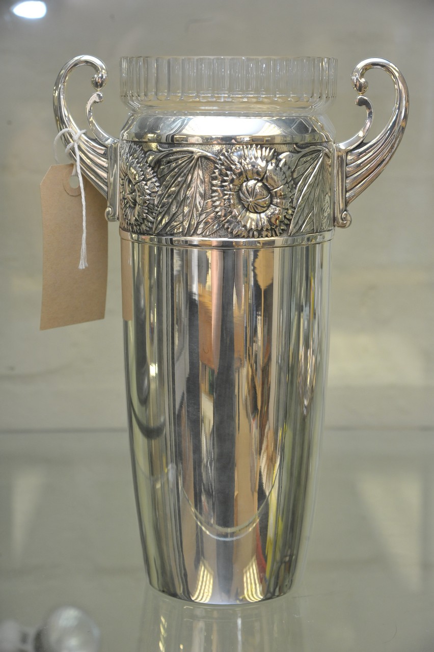 A WMF twin handled vase having repousse floral decorated border and glass liner. Approximately 26.