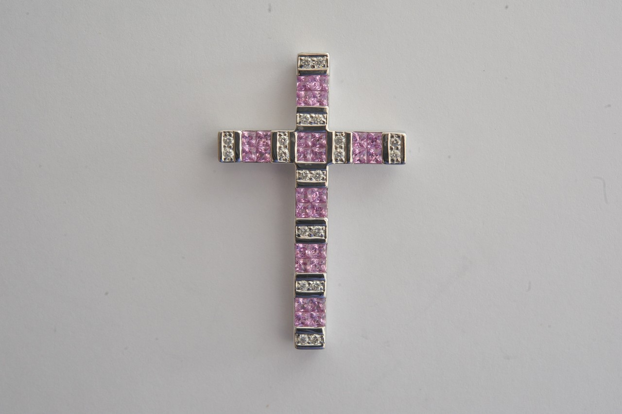 An 18ct white gold pendant in the form of a cross set with pink sapphires and diamonds