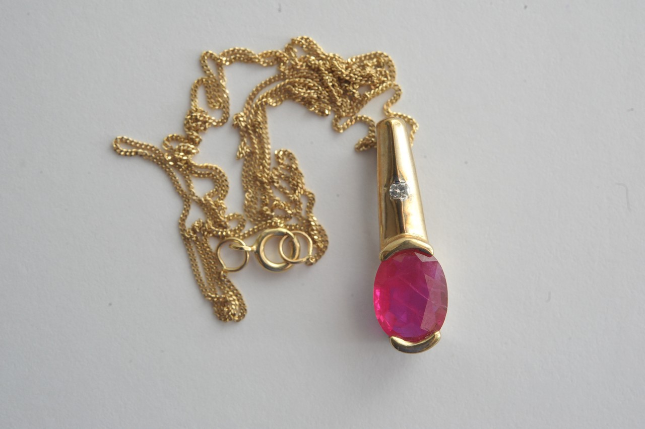A ladies 9ct gold ruby and diamond pendant on fine chain