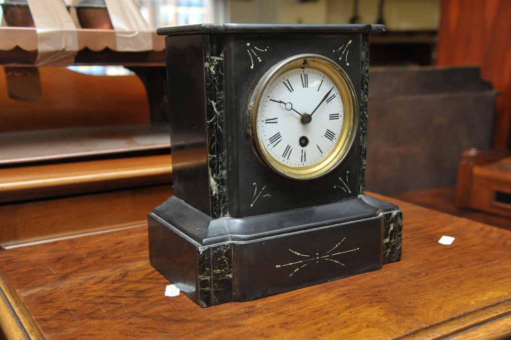 A black slate mantle clock with white enamel dial and Roman numerals