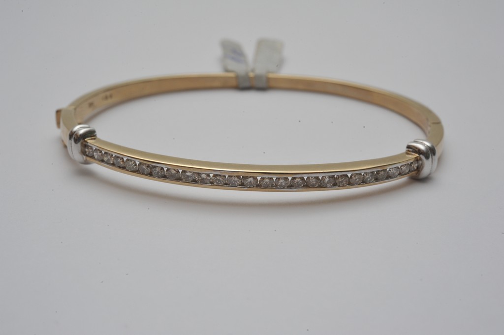 A ladies 9ct yellow gold hinge opening bangle channel set with a single row of brilliant cut