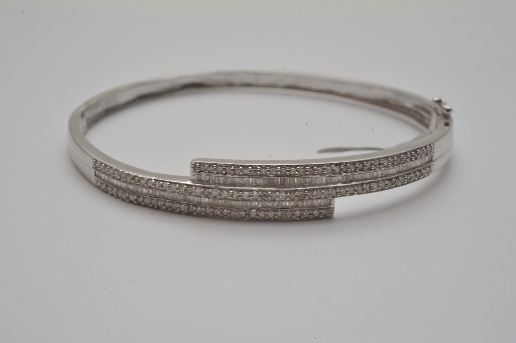 A ladies 18ct white gold bangle profusely set with round and baguette cut diamonds
