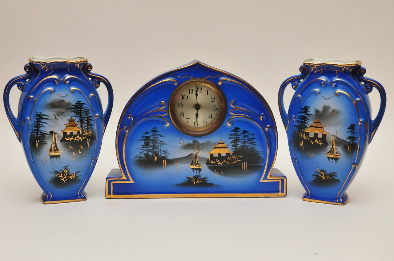 A blue ceramic clock garniture painted with black and gilt decoration in the oriental style