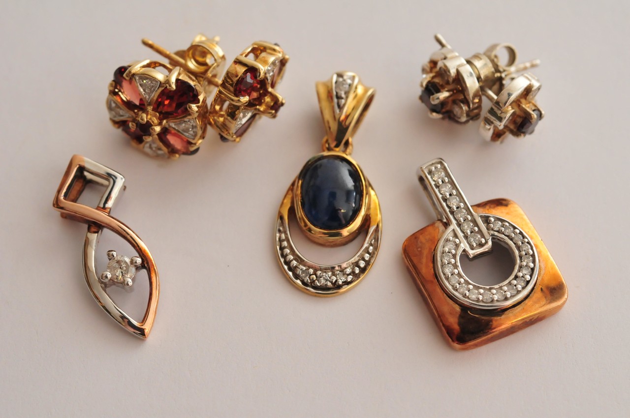 A collection of three ladies gold pendants and two pairs of earrings of varying design all set