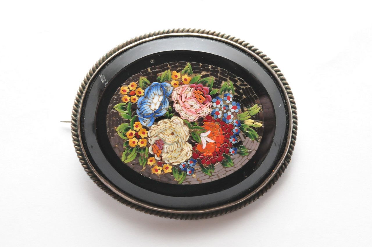 An Italian black stone brooch inlaid with micro mosaic scene of flowers and foliage