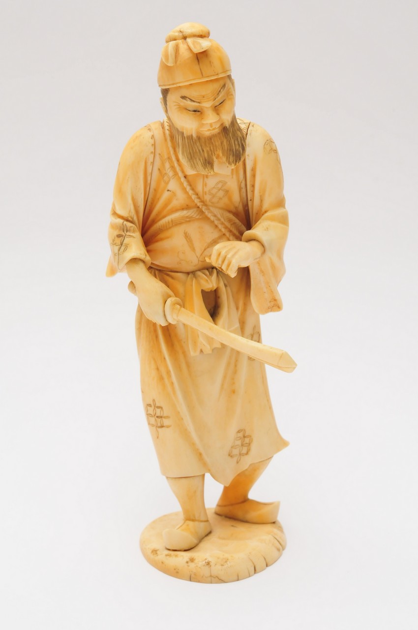 A Japanese carved ivory figure of a bearded man holding a sword, possibly Shoki. Height: 20.5cm
