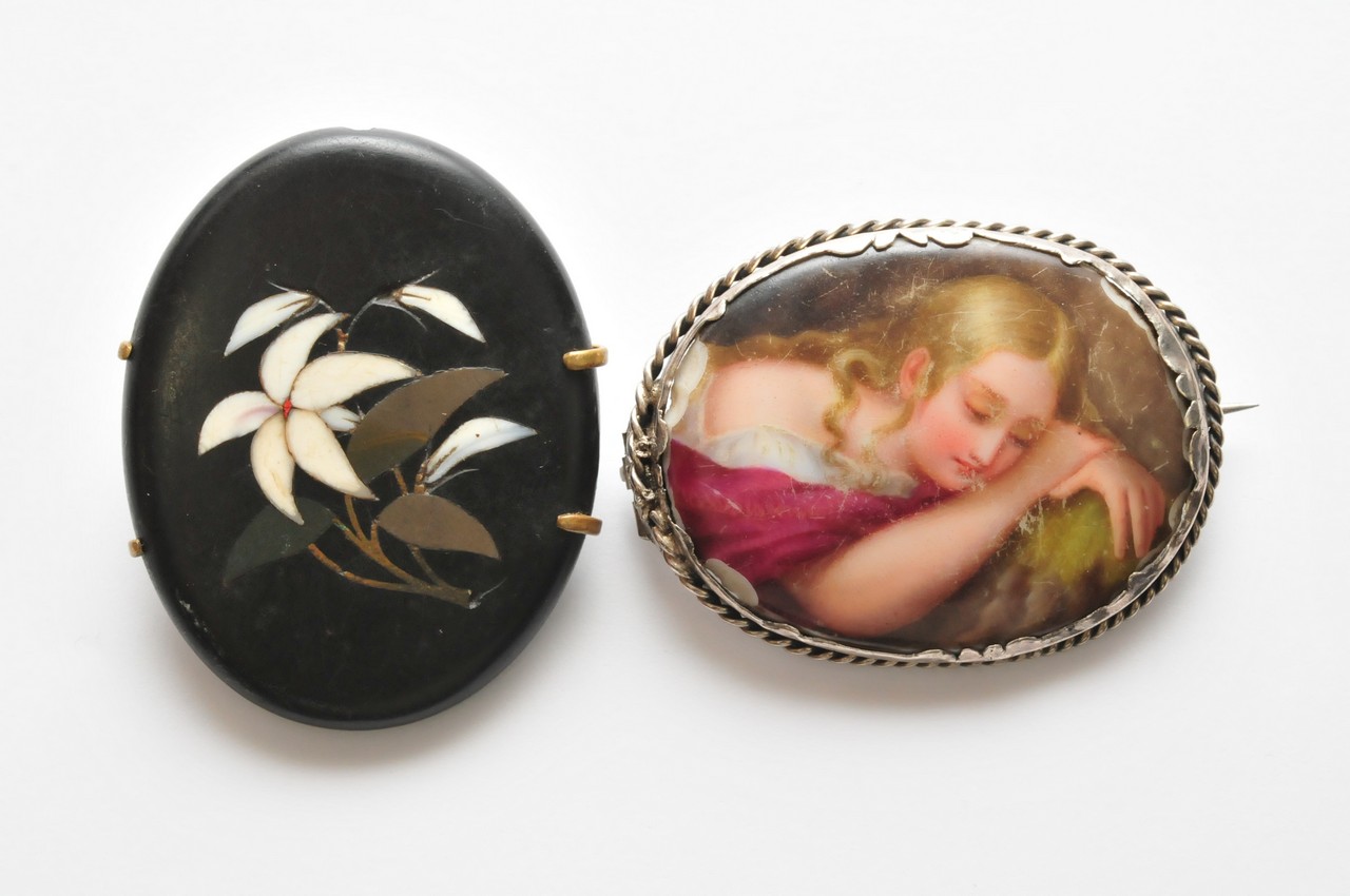 An inlaid Victorian black stone brooch and a painted porcelain oval brooch (damaged)