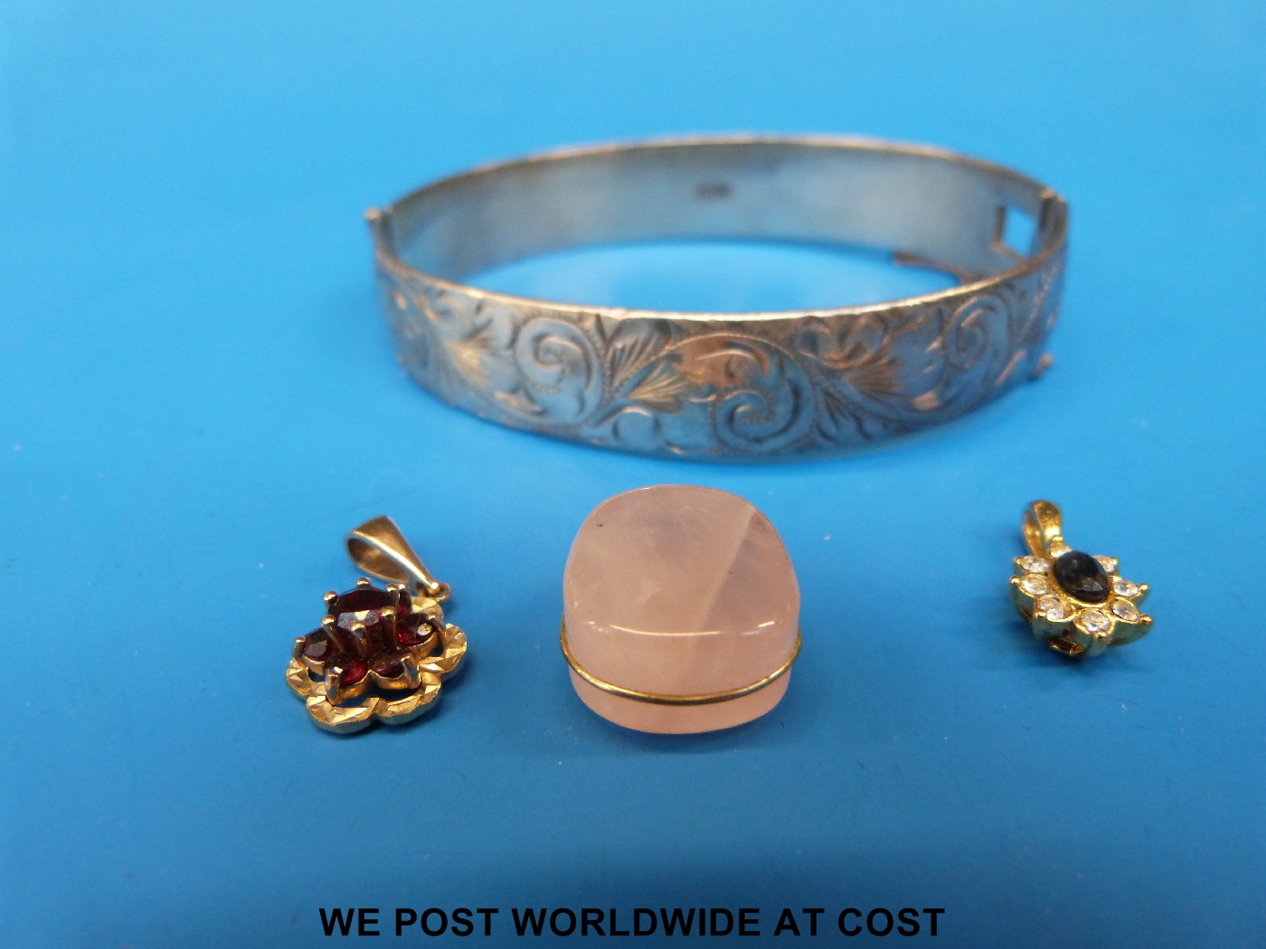 A silver bangle together with three yellow metal pendants set with sapphire, rose quartz etc