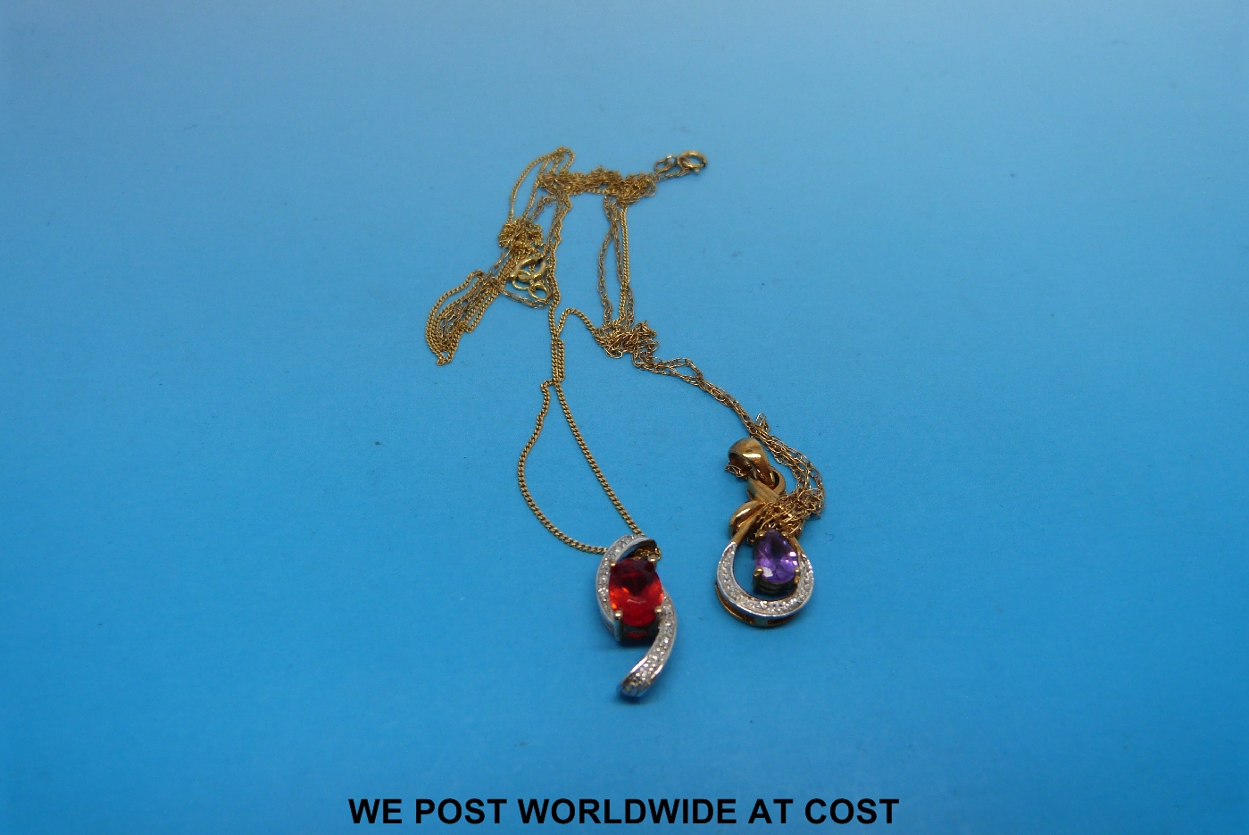 A yellow metal chain and pendant marked 375 gold, set with diamonds and a red stone, together with a