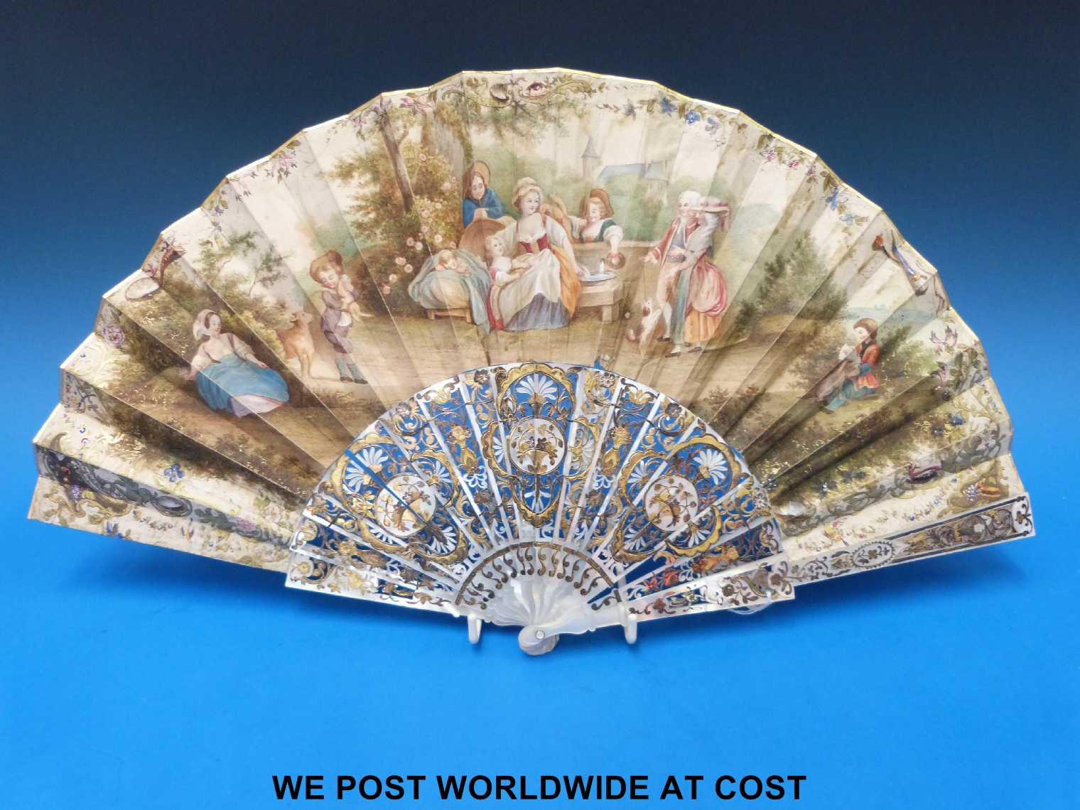 A 19thC pierced mother of pearl, silver and silver gilt inlaid fan decorated with hand painted scene