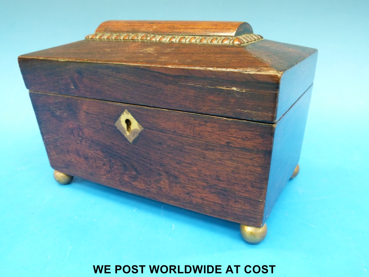 A rosewood sarcophagus tea caddy raised on brass ball feet, width 21cm