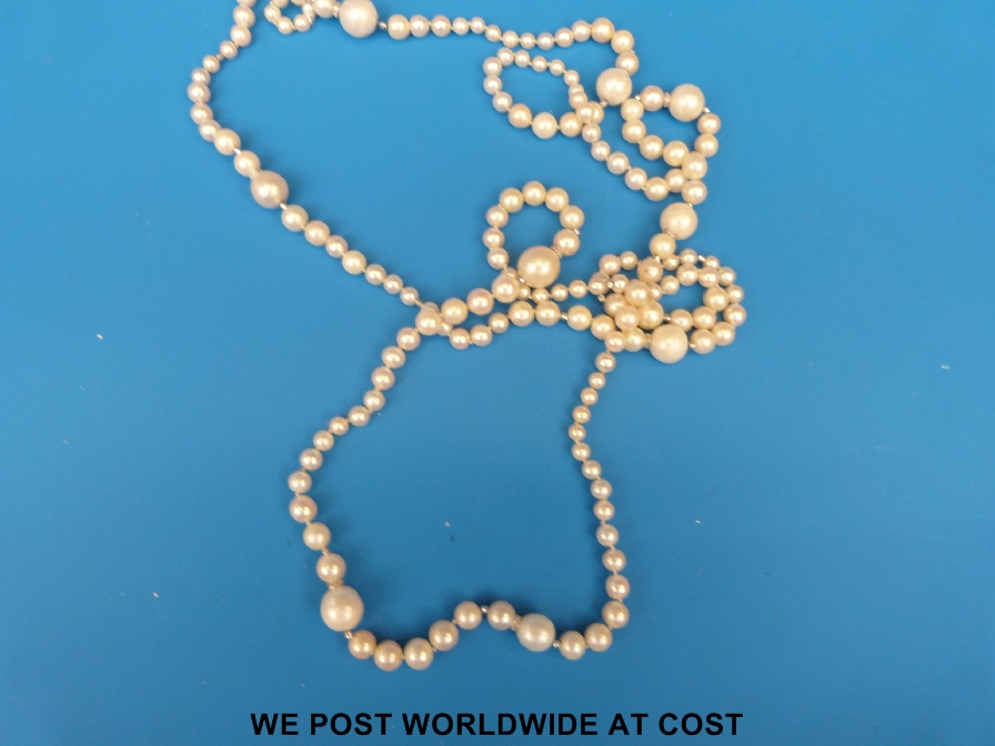 An exceptionally long pearl necklace inset with diamond spacers and with diamond set clip