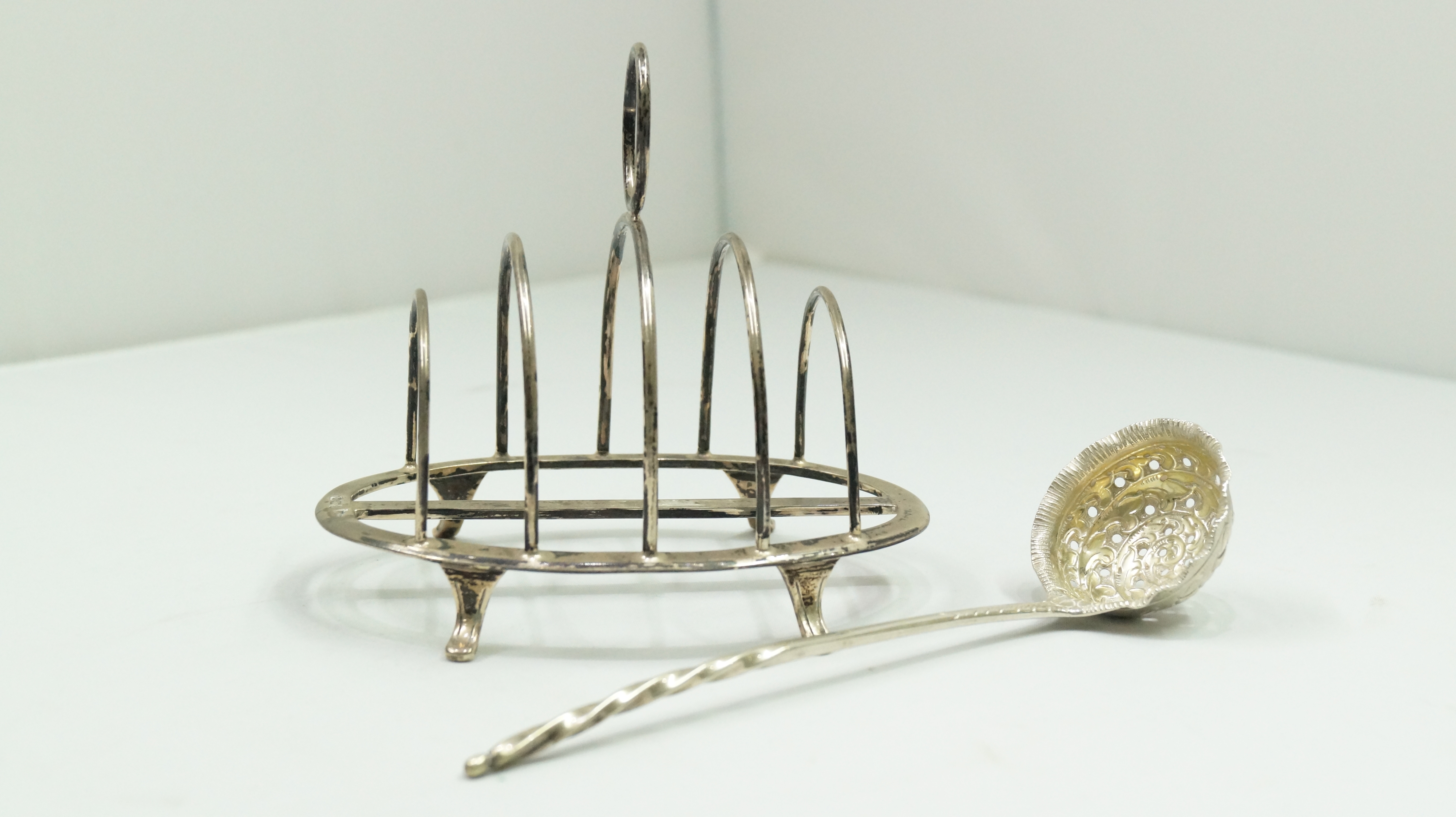 A silver toast rack, by Walker & Hall, Sheffield 1913, 12.5cm, 116g; together with a plated sifter