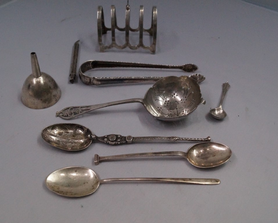 A silver toast rack; together with a silver pencil cover; five pieces of silver cutlery; and two