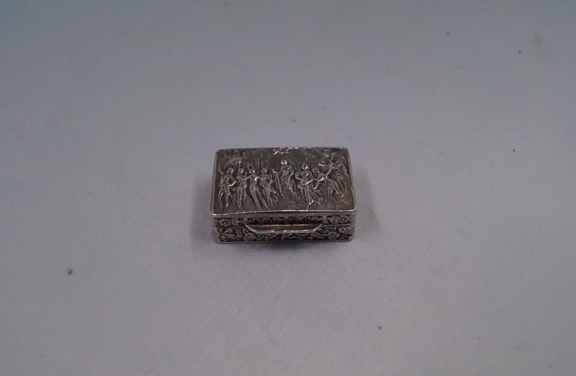 A continental silver pill box, decorated Bacchanalian figures to lid, with fruiting vine and