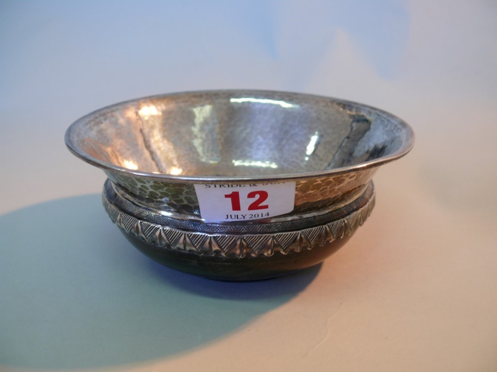 A hammered silver mazer bowl, by A E Jones, Birmingham 1922, on wooden base, 14cm.