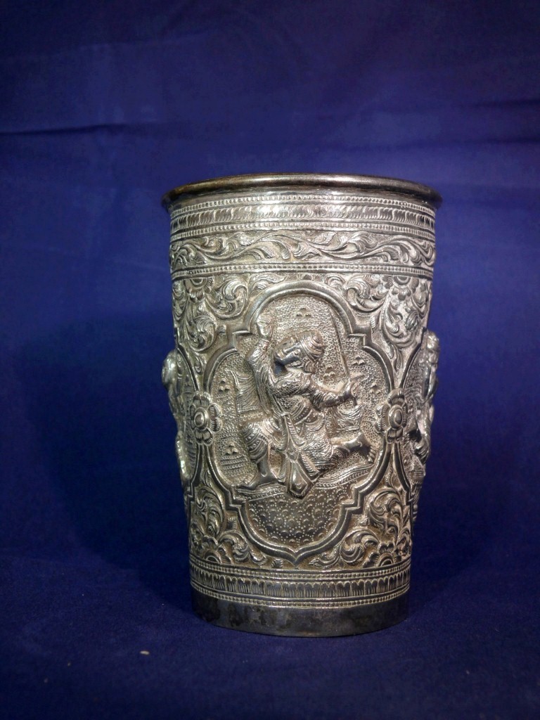 An Eastern metal beaker, having four panels decorated figures, 10.5cm.