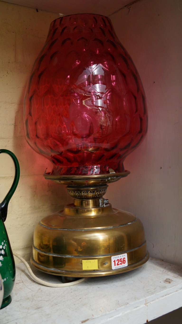 An antique brass and cranberry glass lamp.