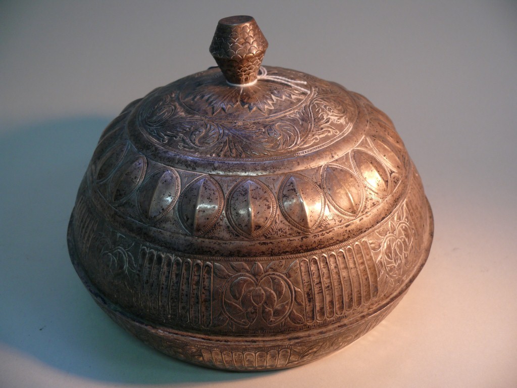 An Eastern white metal bowl and cover, having embossed decoration overall, 22cm diameter.