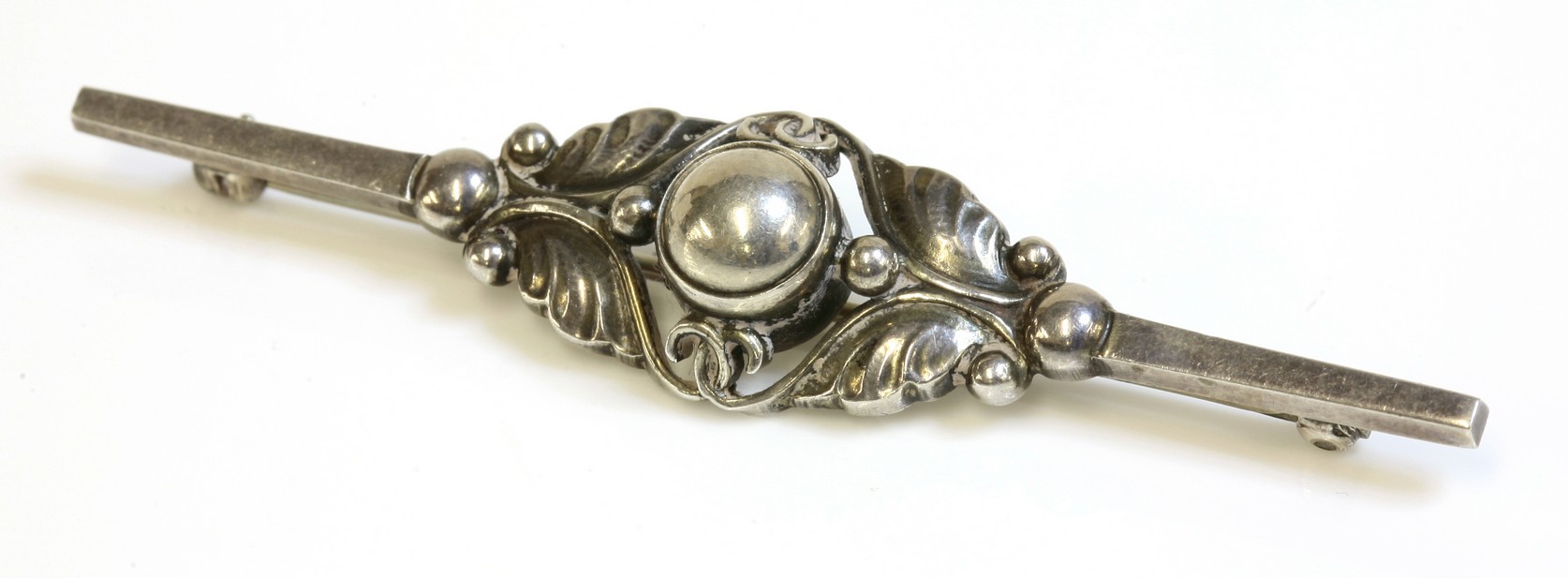 A sterling silver Georg Jensen bar brooch, No. 224B,
with a half bead centre and foliate surround,