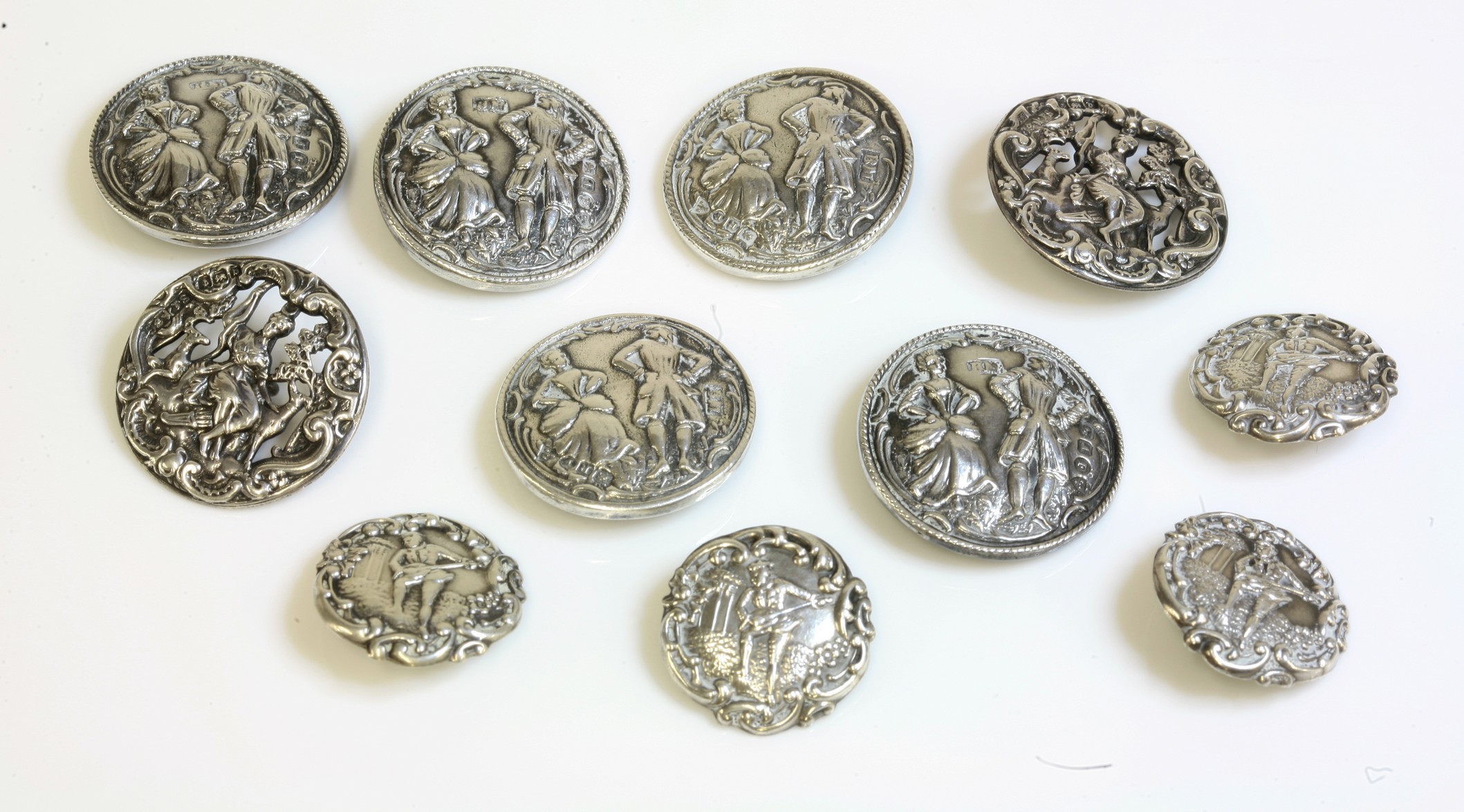 A set of five sterling silver rococo style buttons,
by B Muller and Sons, depicting a couple in 18th