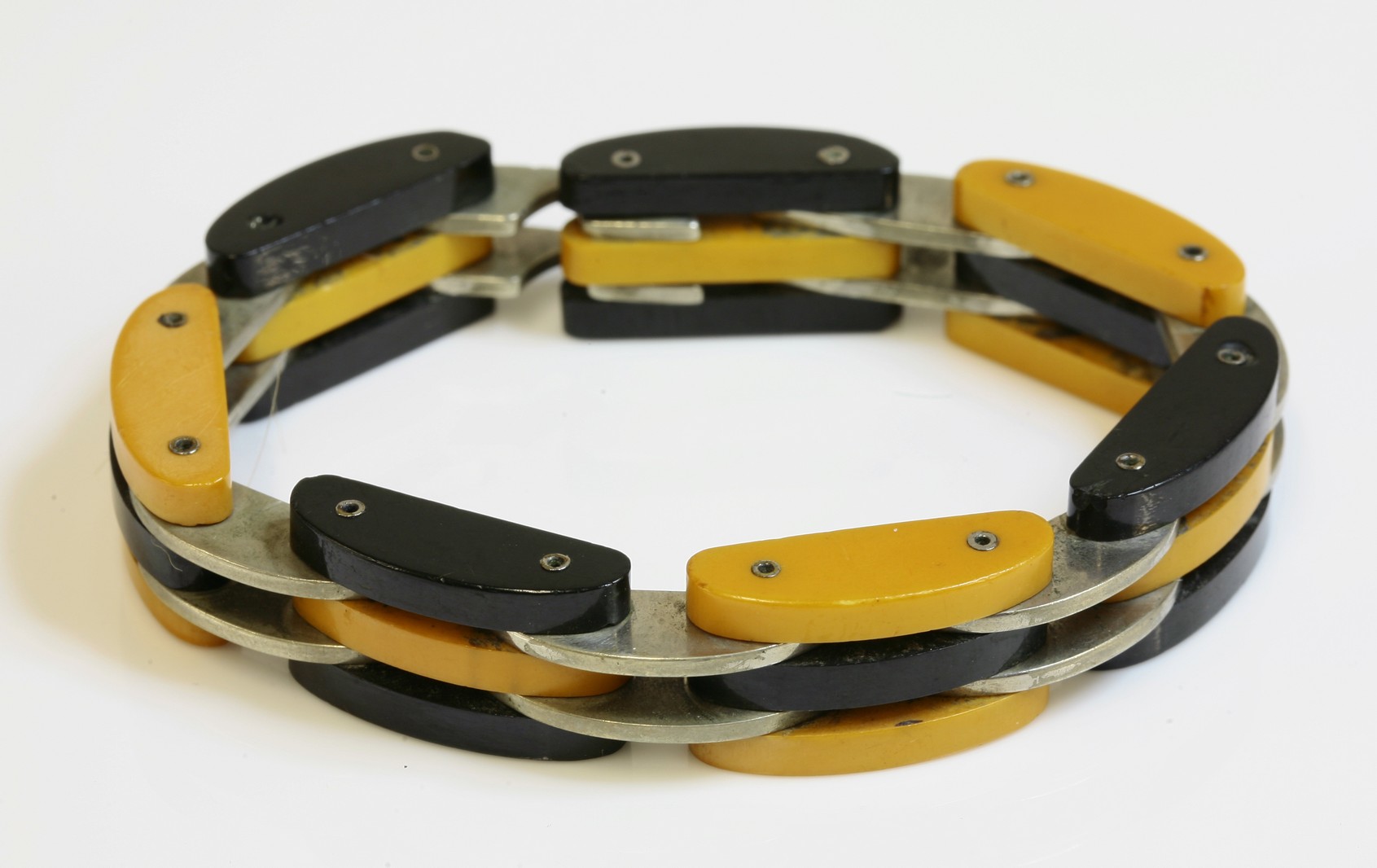 An Art Deco Bakelite and white metal bracelet,
with sets of three arched Bakelite links in