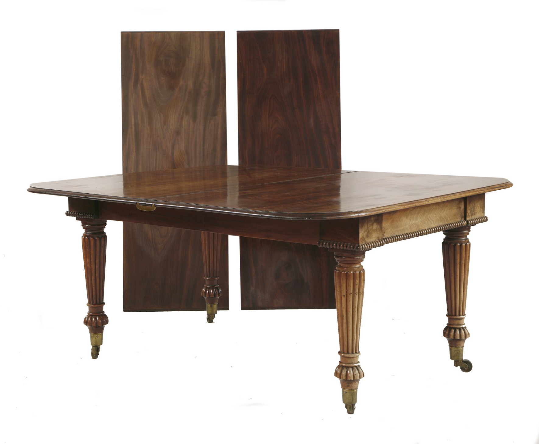 A Victorian mahogany dining table,
with two extra leaves, raised on turned and reeded supports,