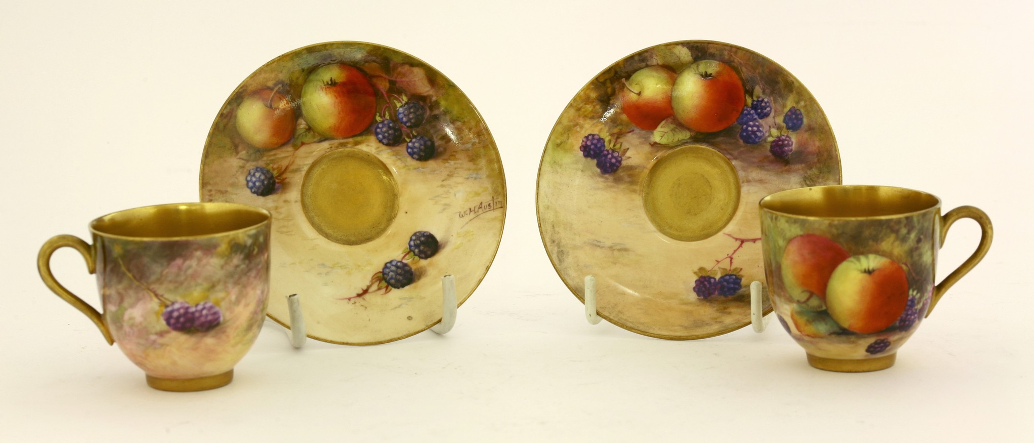 A pair of Royal Worcester bone china Coffee Cups and Saucers,
each painted with autumn fruit by W