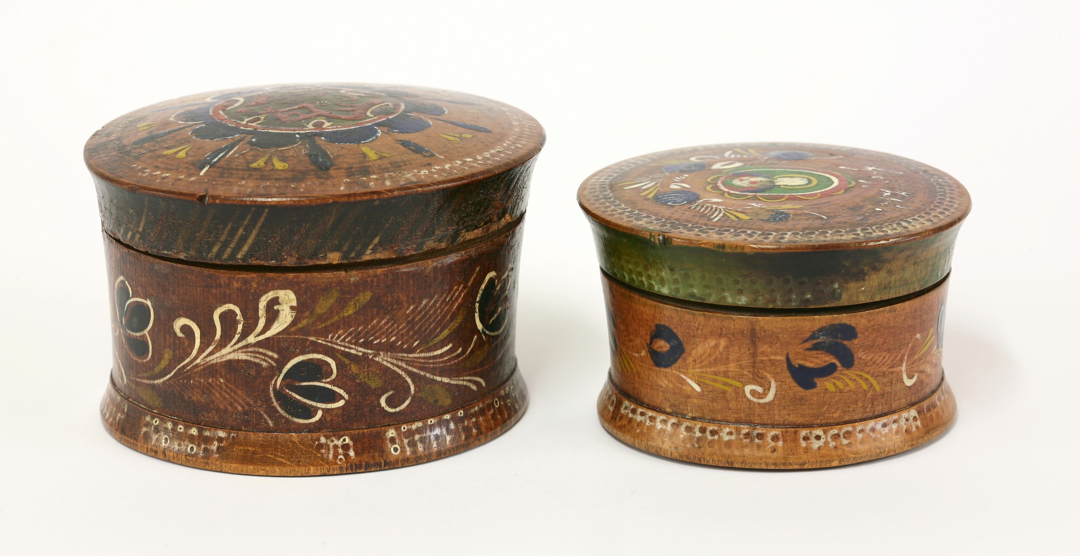 Two Continental turned softwood boxes and covers, 
each painted with trailing flowers, the larger