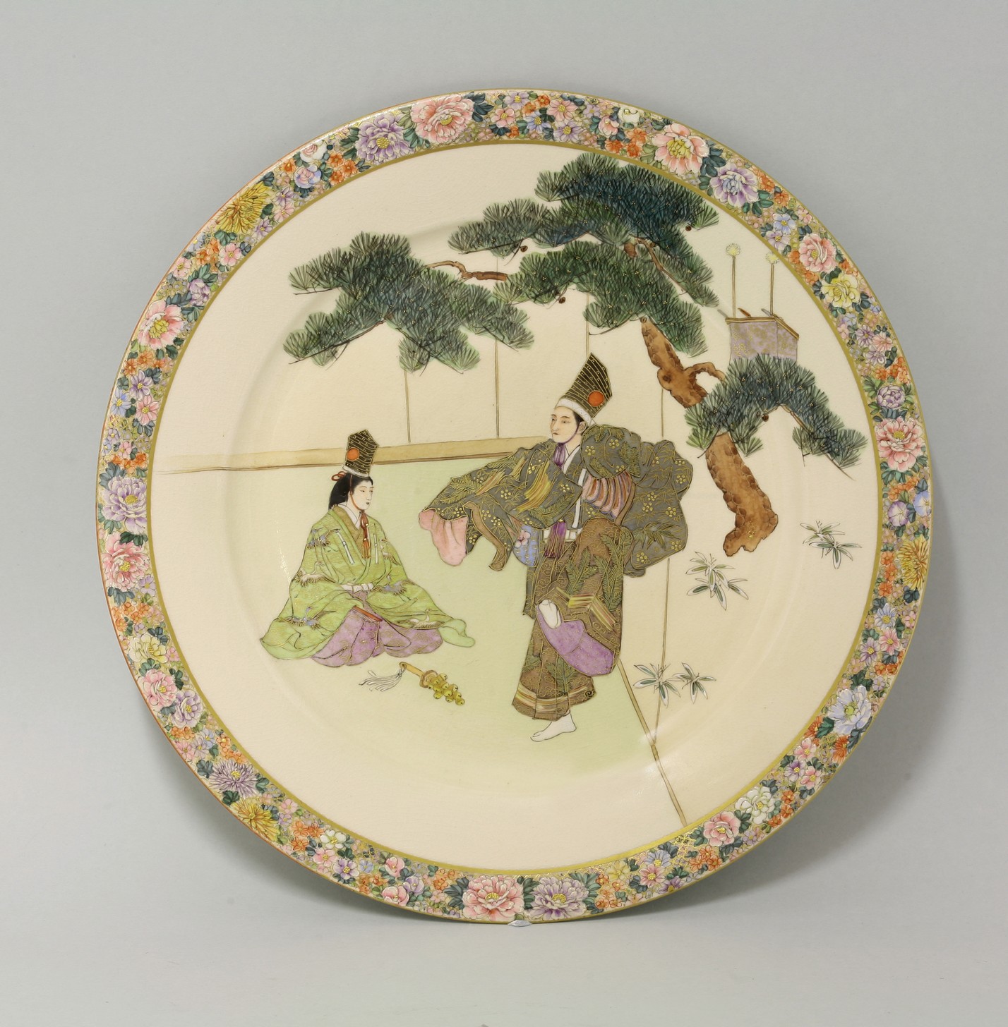 A Kinkozan Dish,
c.1920, enamelled and gilt with a priest and priestess kneeling or dancing under