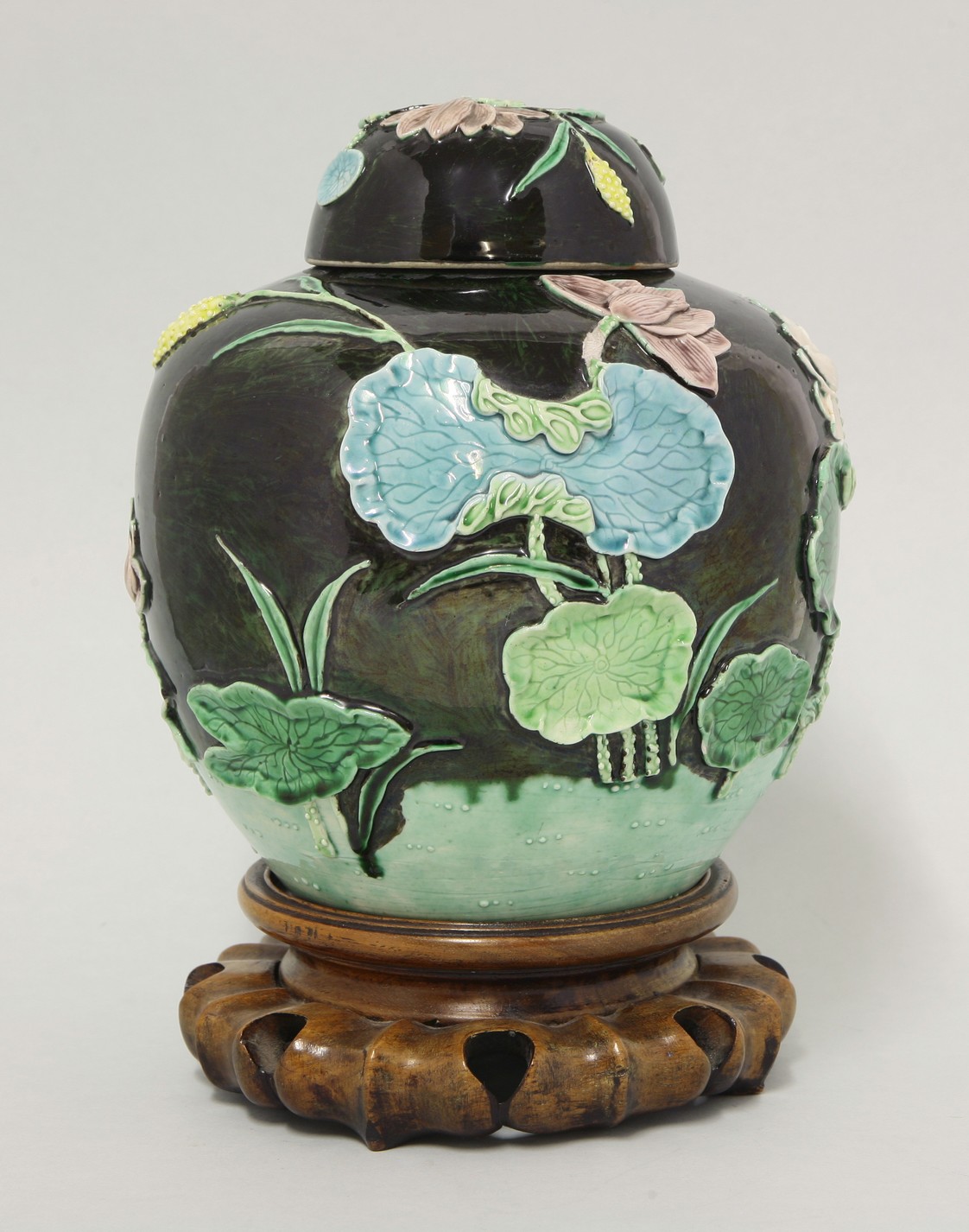 A moulded Wang Bingrong Jar and Cover,
c.1870, the black ground with relief lotus and a crane,