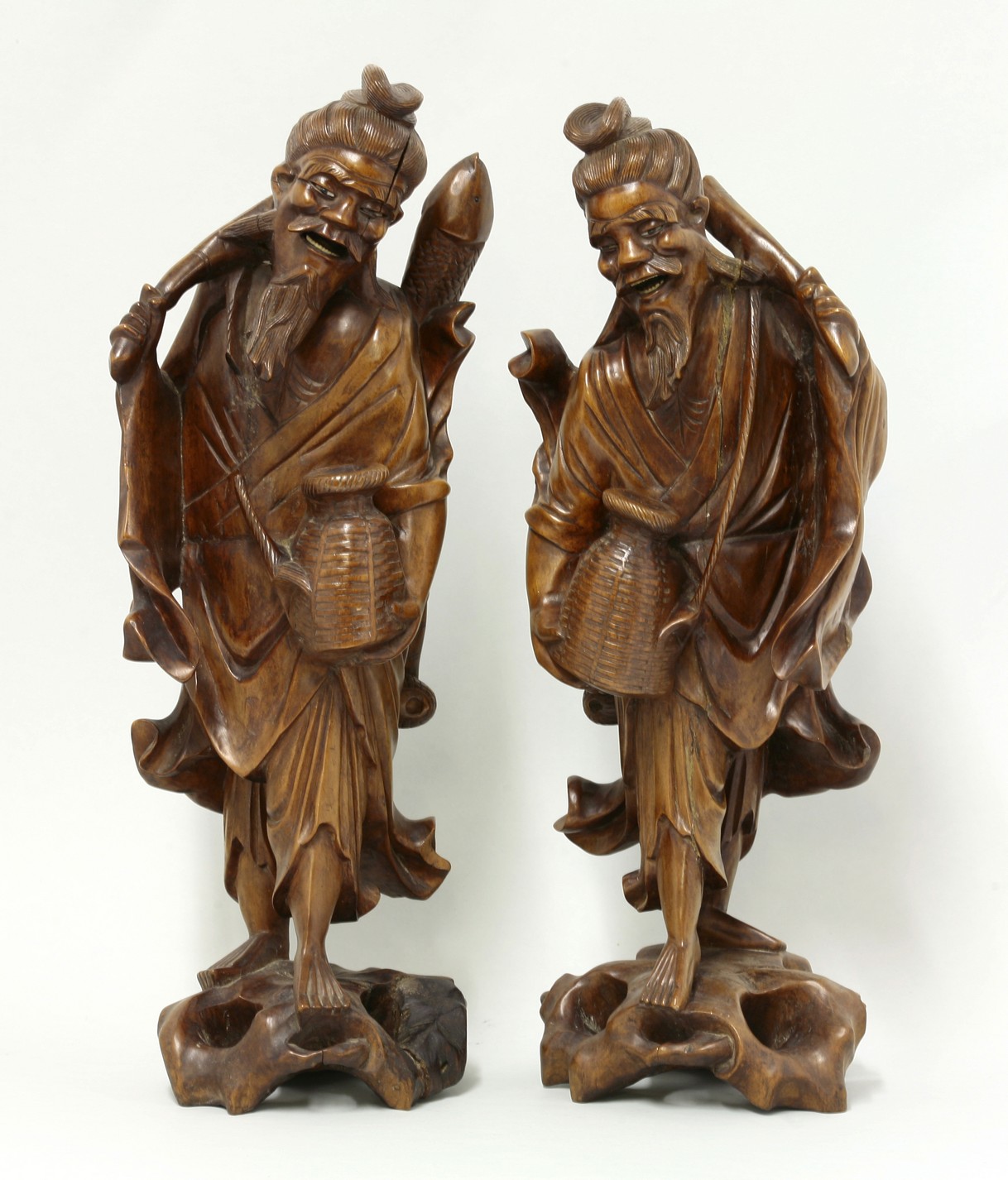 A pair of wood Fishermen,
late 19th century, each carved with creel, fish or oar, the eyes and teeth