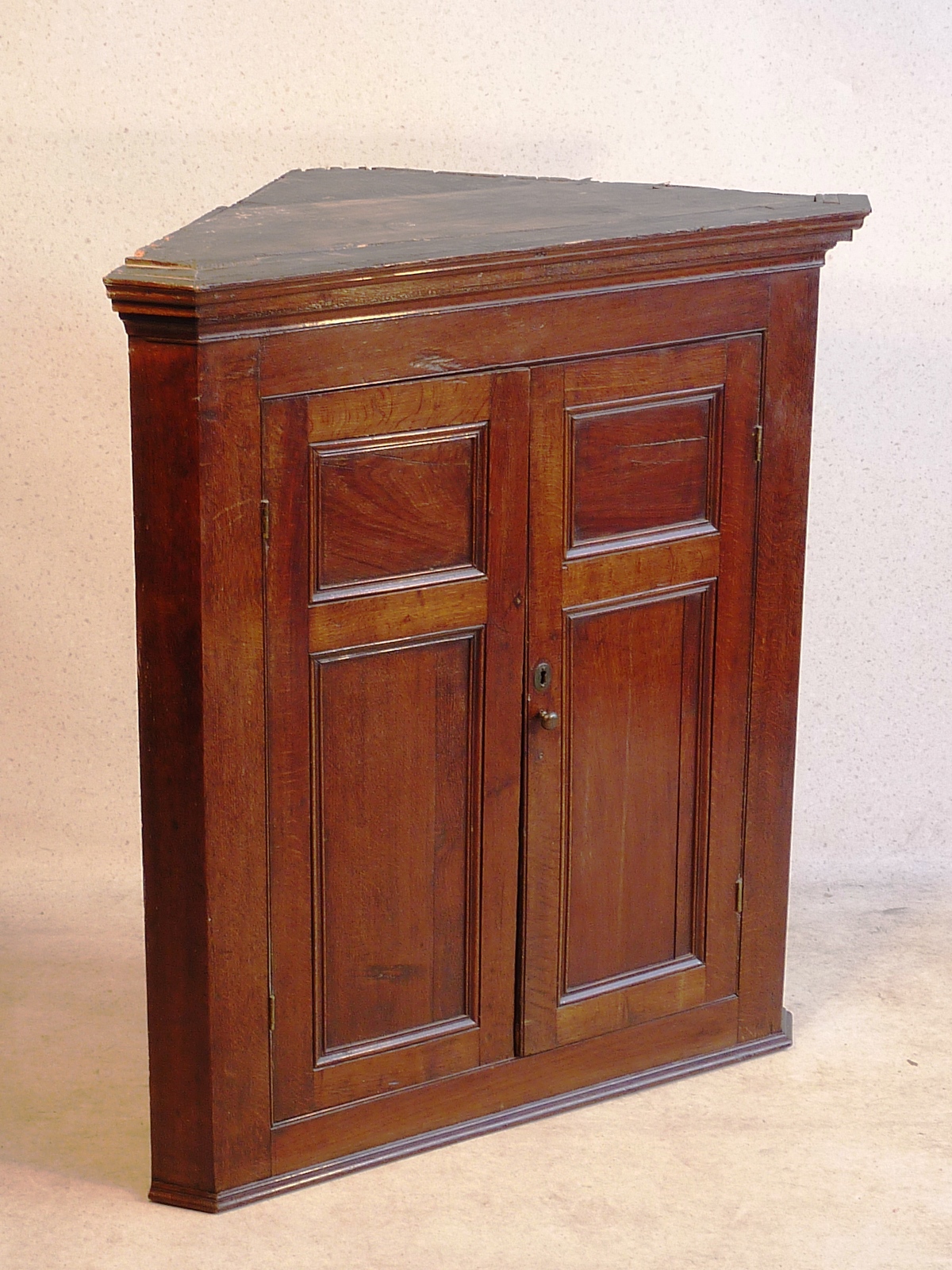 A late 18th Century oak hanging Corner Cupboard of large proportions, the two panelled doors